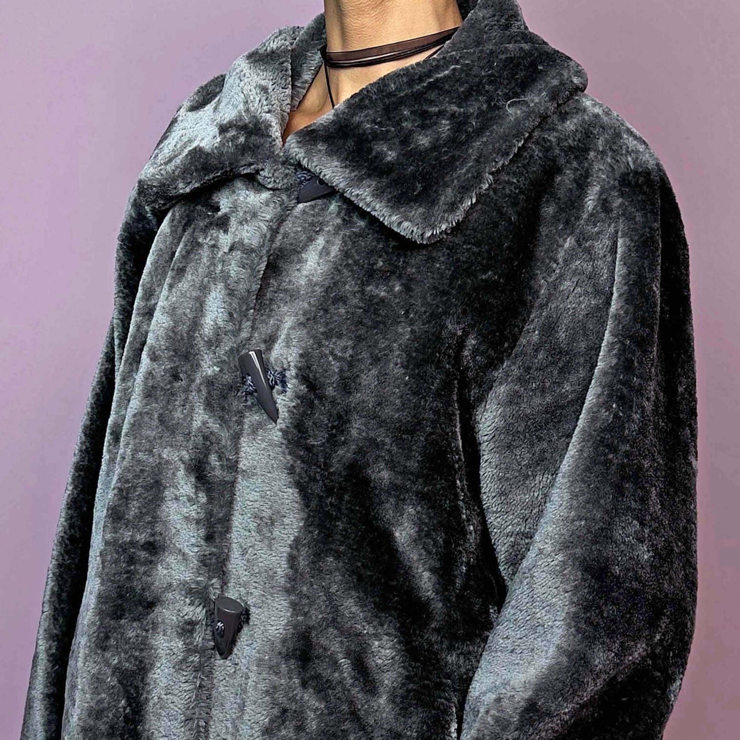 The Vintage 90s Gray Faux Fur Coat is a cozy and stylish outerwear piece featuring a plush faux fur design, a toggle-front closure, a wide collar, and pockets. Perfect for your winter wardrobe.