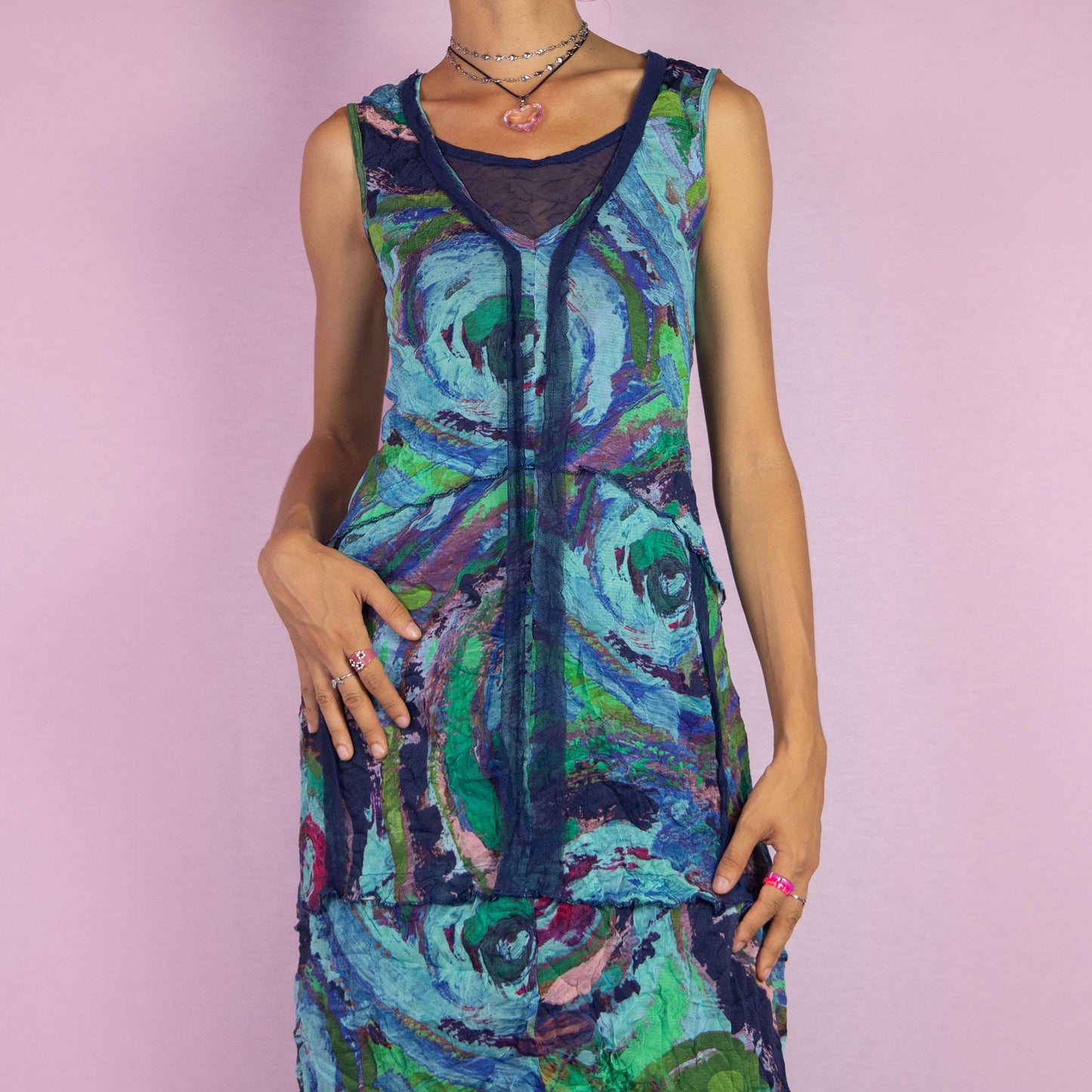 The Y2K Art Print Mesh Dress is a vintage 2000s piece featuring a flowing A-line silhouette with an abstract, artistic print in vibrant tones of blue, green, and purple. Crafted from lightweight, semi-sheer mesh fabric, it offers a layered design
