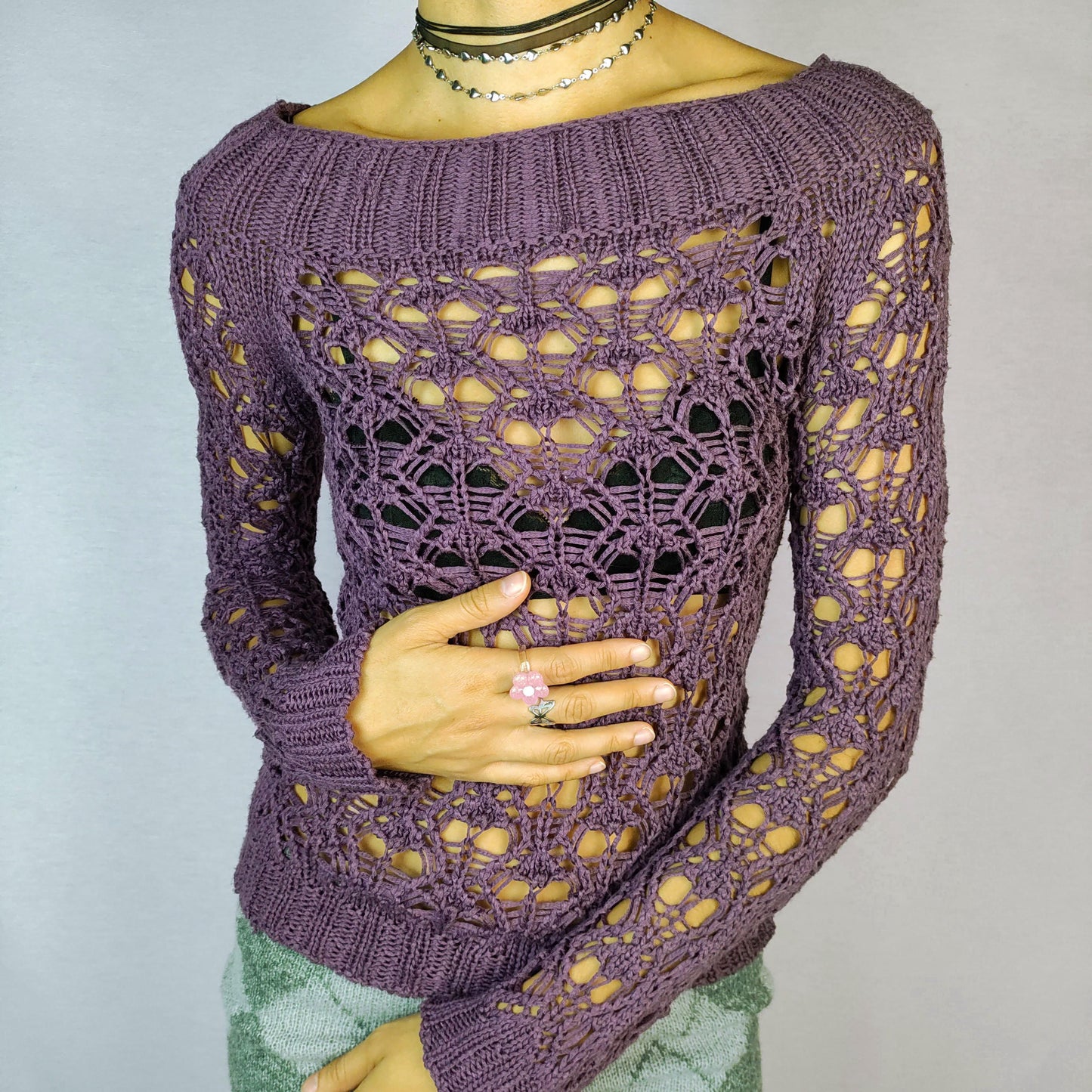 The Y2K Purple Crochet Boat Sweater is a vintage 2000s pullover featuring an intricate crochet-knit design, a boat neckline and long sleeves.