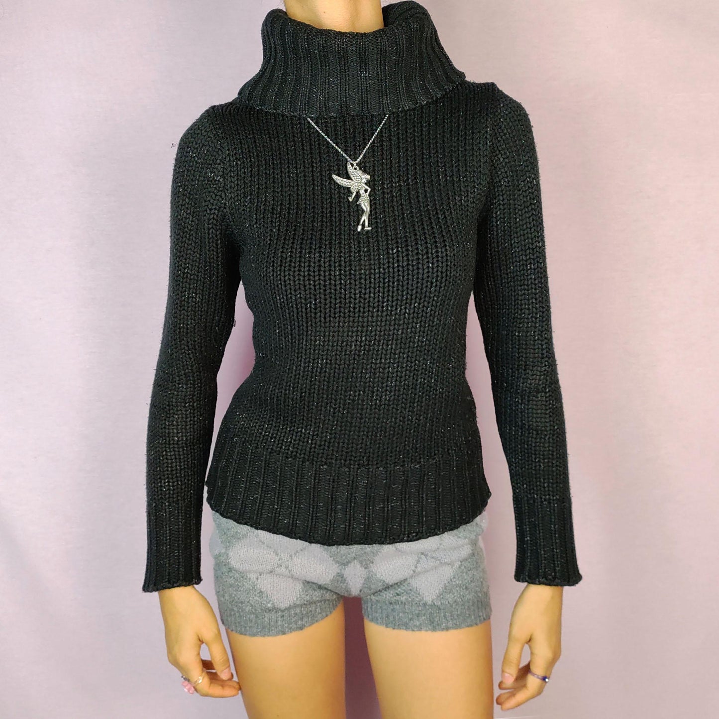 The Y2K Black Turtleneck Sweater is a vintage 2000s staple featuring a ribbed-knit design and a cozy oversized turtleneck. This timeless pullover is crafted from a stretchy fabric, offering both comfort and warmth. Perfect for casual winter looks.