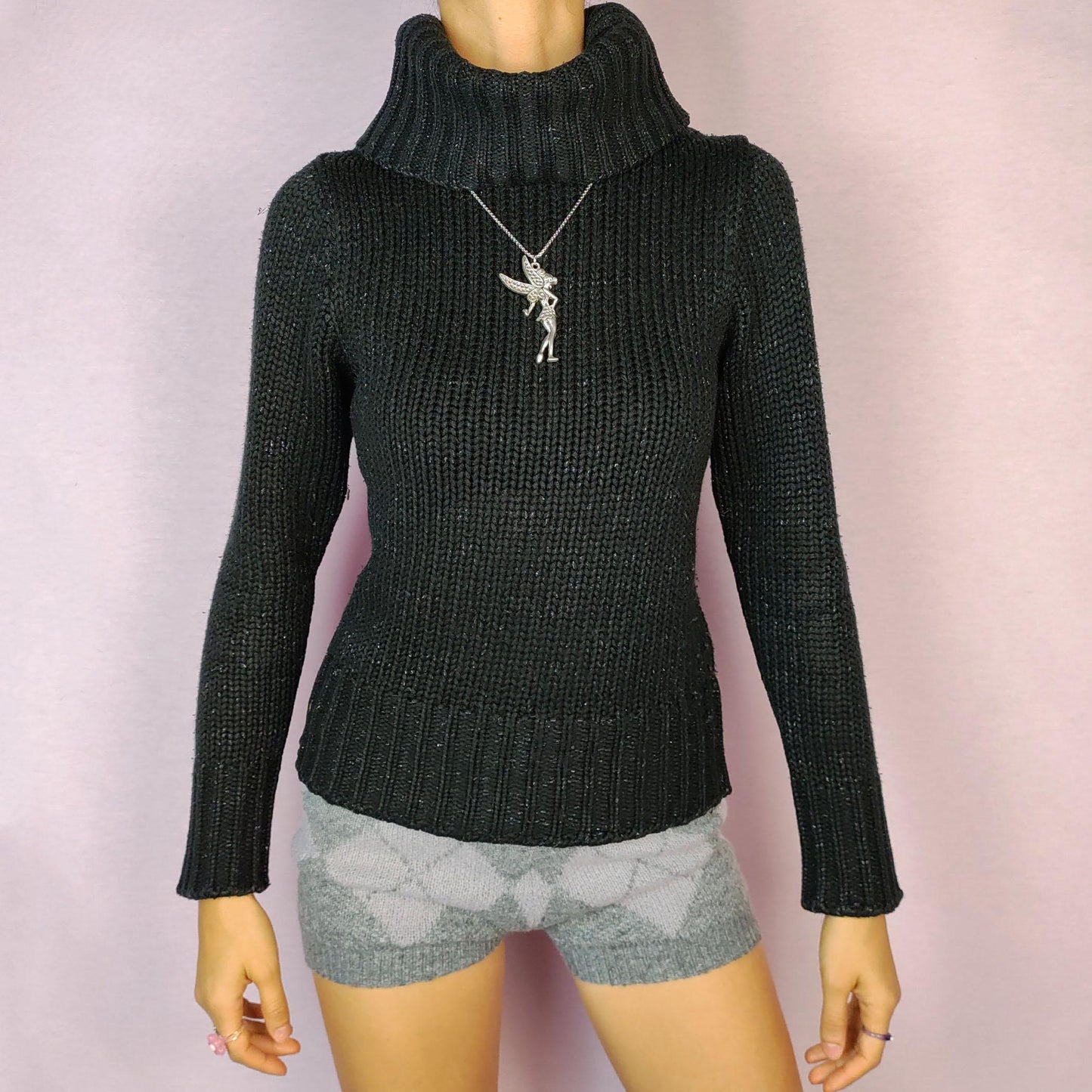 The Y2K Black Turtleneck Sweater is a vintage 2000s staple featuring a ribbed-knit design and a cozy oversized turtleneck. This timeless pullover is crafted from a stretchy fabric, offering both comfort and warmth. Perfect for casual winter looks.