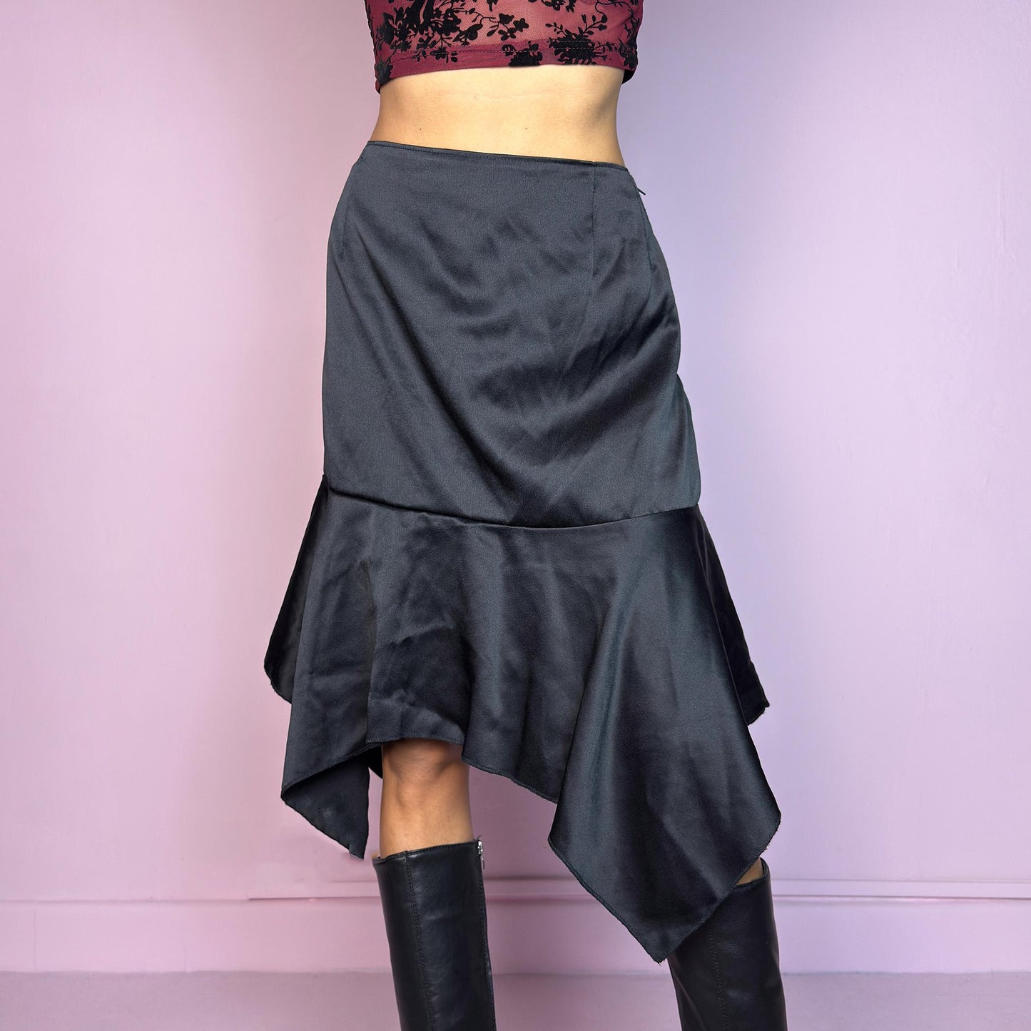 The Y2K Black Satin Asymmetric Skirt is a vintage 2000s stylish piece, featuring a satin-like finish with an asymmetrical handkerchief hemline for a dramatic flair and a size zipper closure. Perfect choice for party nights. Adult World Shop