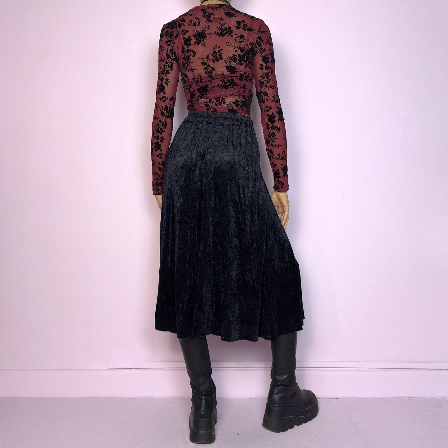 The Vintage 90s Black Velvet Midi Skirt is crafted from soft velvet and features an elastic waistband detail with button accents and a flowing A-line silhouette. Ideal for night parties and embodies a whimsical goth aesthetic. Adult World Shop