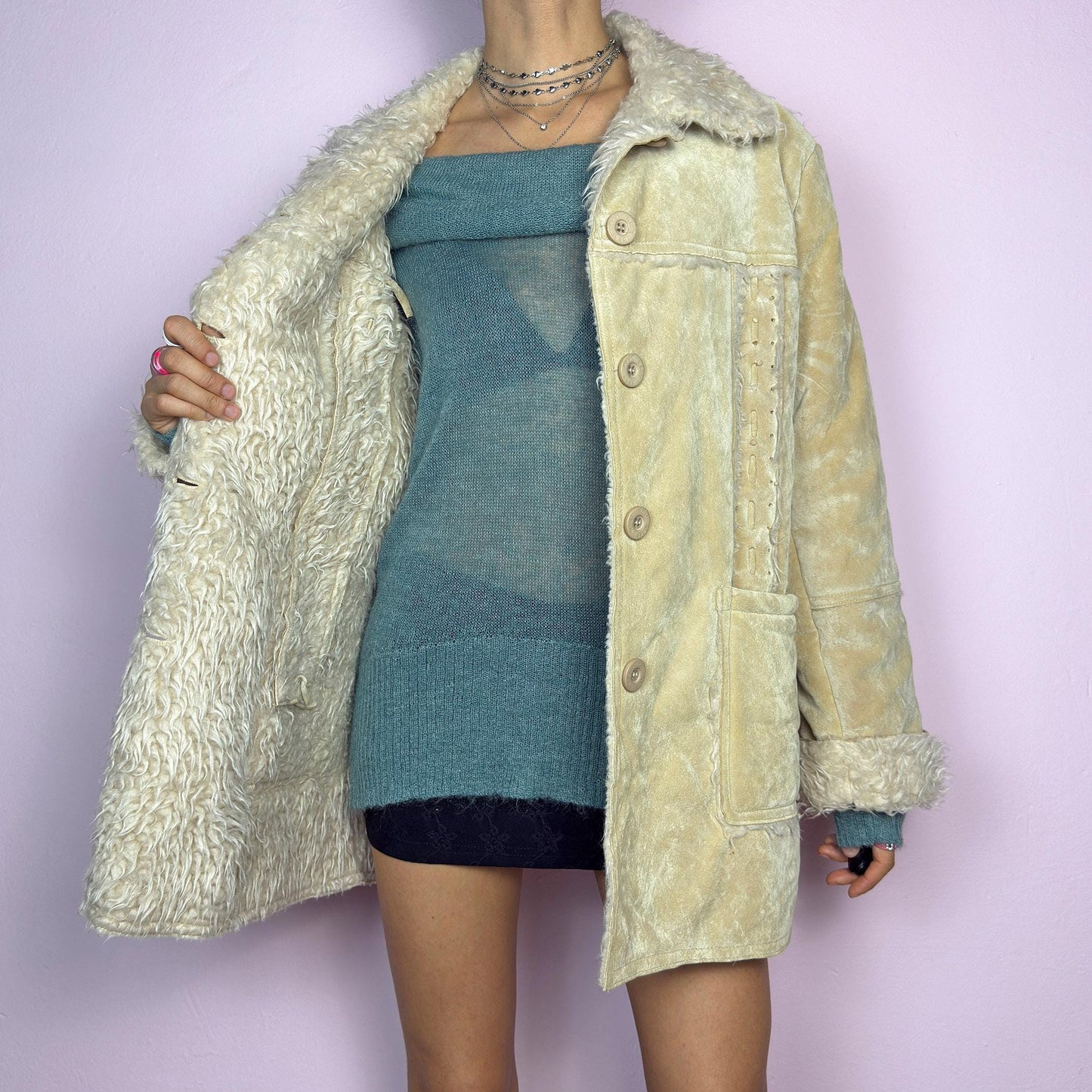 The Y2K Beige Faux Fur Suede Jacket is a vintage 2000s cozy outerwear piece featuring a soft faux suede finish in a beige tone, a faux shearling-lined collar and cuffs for added warmth, a button-front closure and pockets. adult world shop