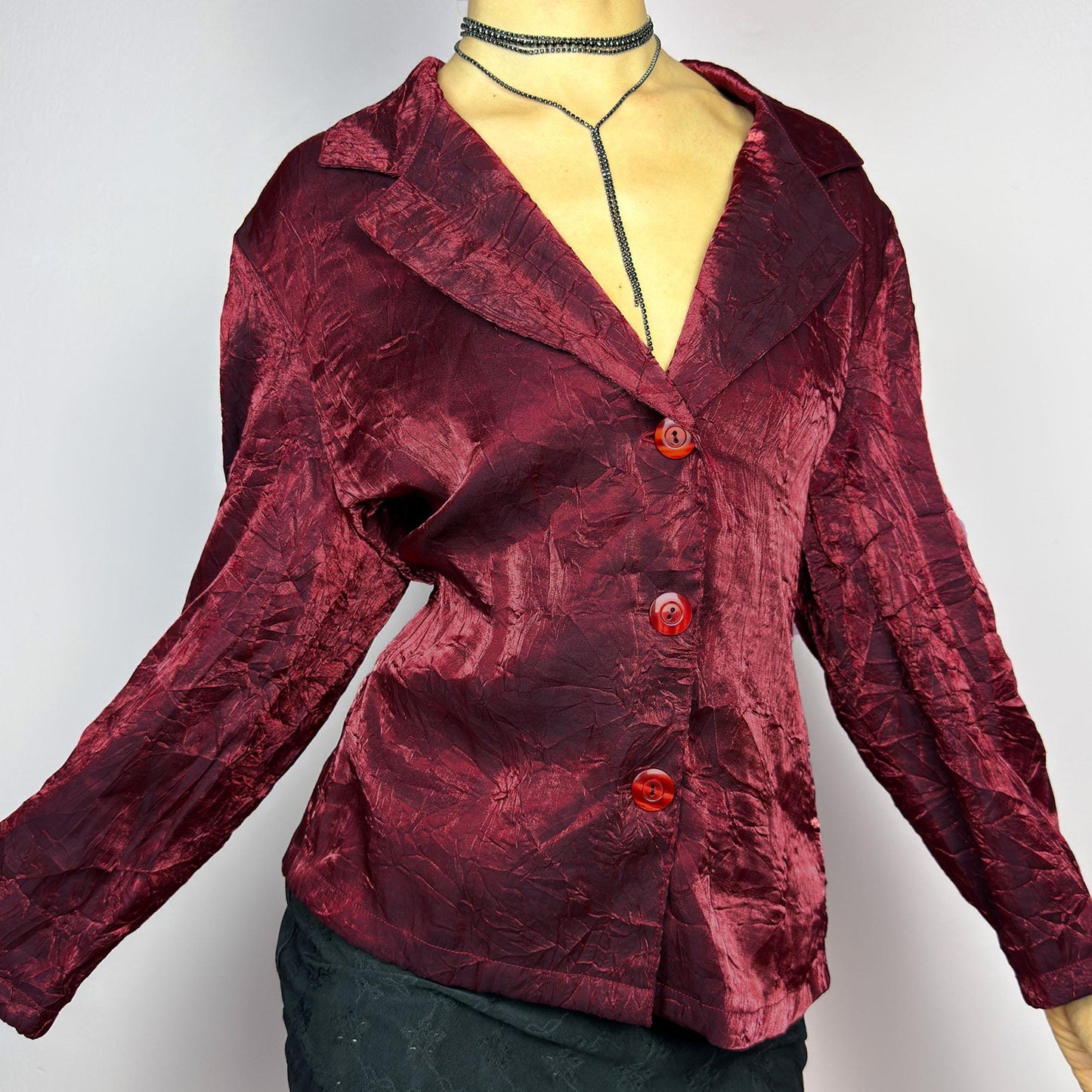 The Vintage 90s Red Iridescent Jacket is a striking and glamorous piece featuring a textured, crinkled design with a luxurious, iridescent sheen. This button-up jacket showcases a deep red tone, wide lapels, and bold red buttons. adult world shop