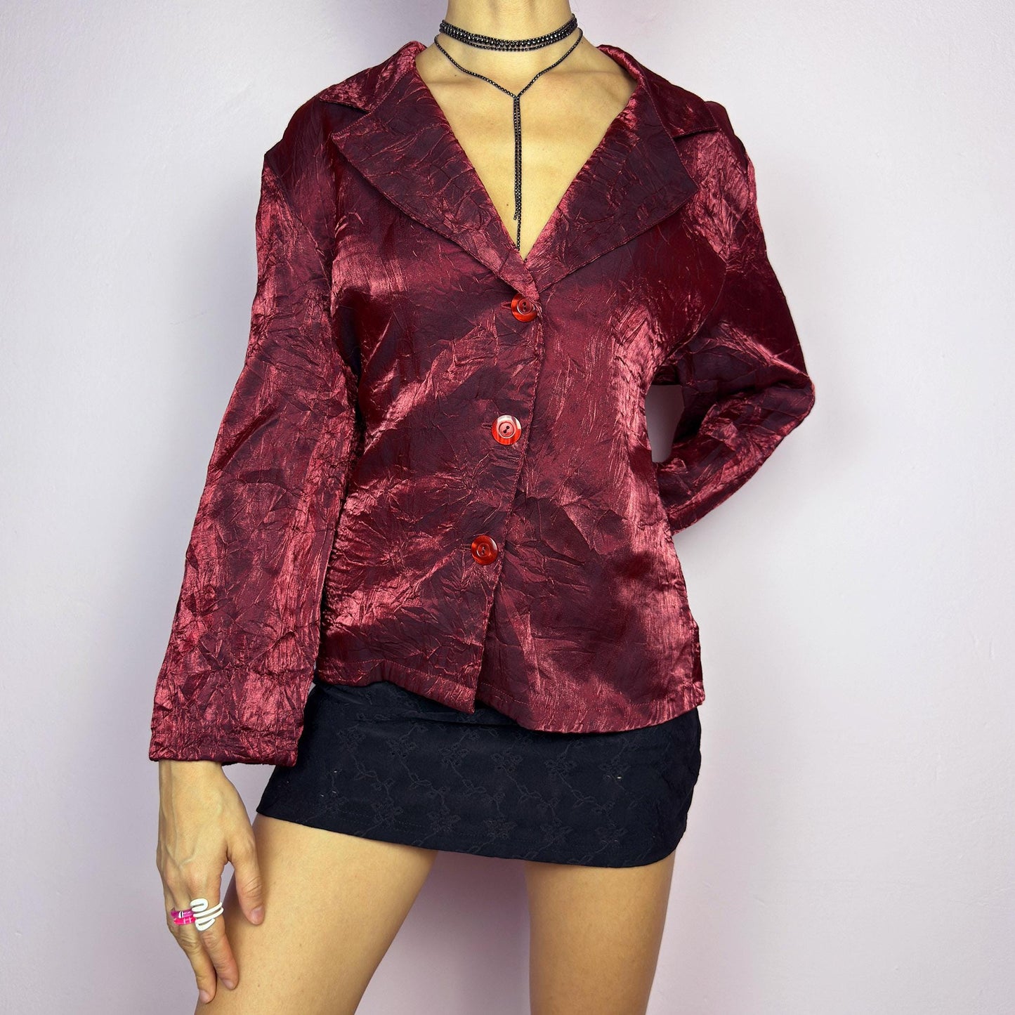 The Vintage 90s Red Iridescent Jacket is a striking and glamorous piece featuring a textured, crinkled design with a luxurious, iridescent sheen. This button-up jacket showcases a deep red tone, wide lapels, and bold red buttons. adult world shop