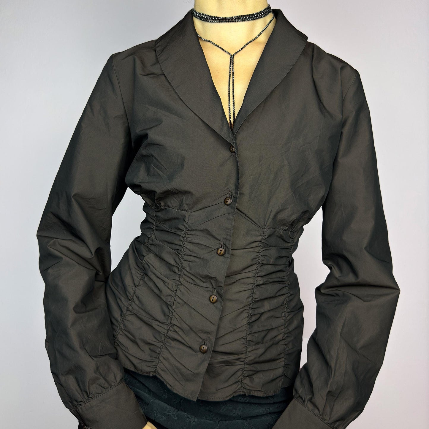 The Vintage 90s Brown Ruched Blouse features a structured yet feminine design with ruched detailing on both the front and back, creating a flattering silhouette. Crafted in a deep brown tone, it includes a tailored collar. adult world shop