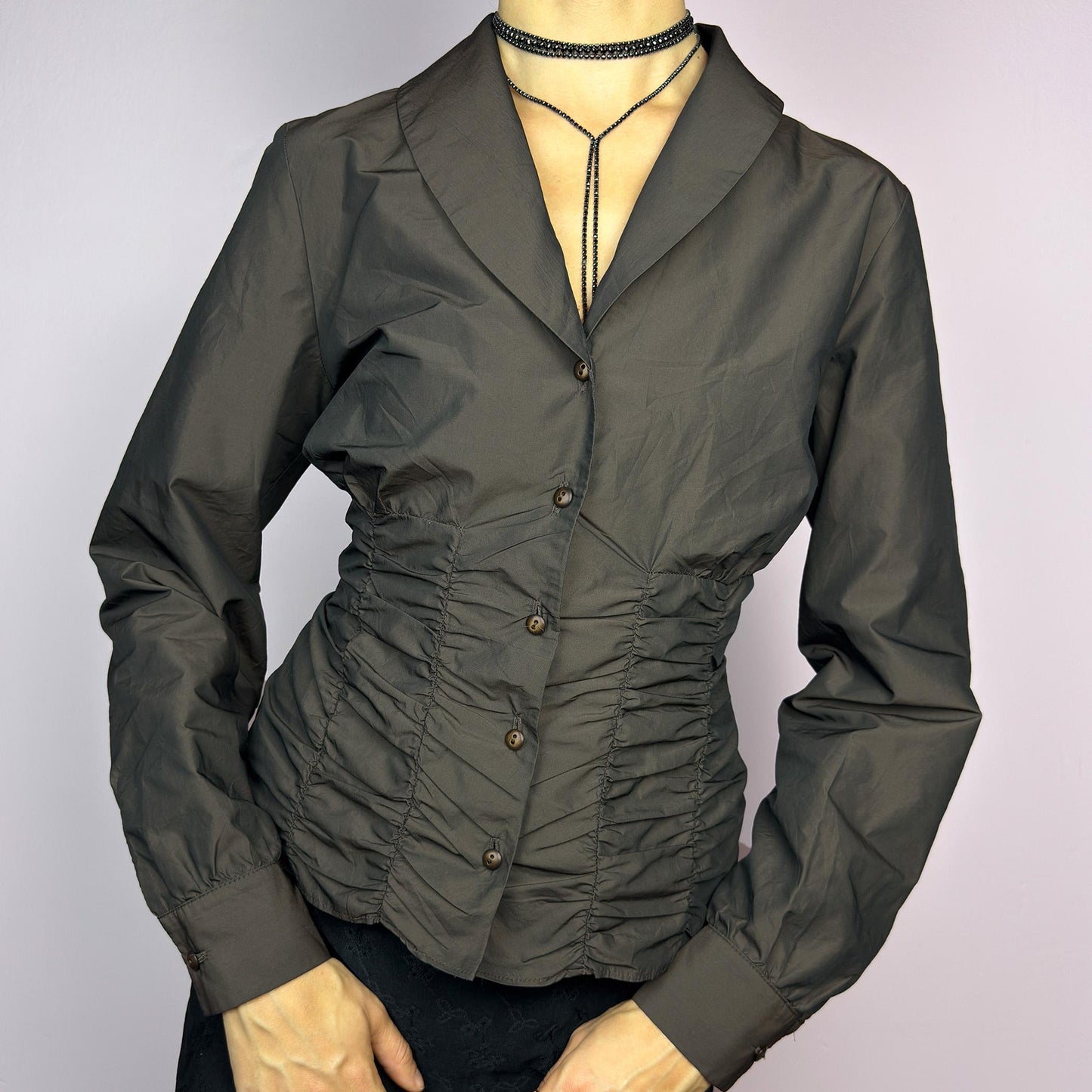 The Vintage 90s Brown Ruched Blouse features a structured yet feminine design with ruched detailing on both the front and back, creating a flattering silhouette. Crafted in a deep brown tone, it includes a tailored collar. adult world shop