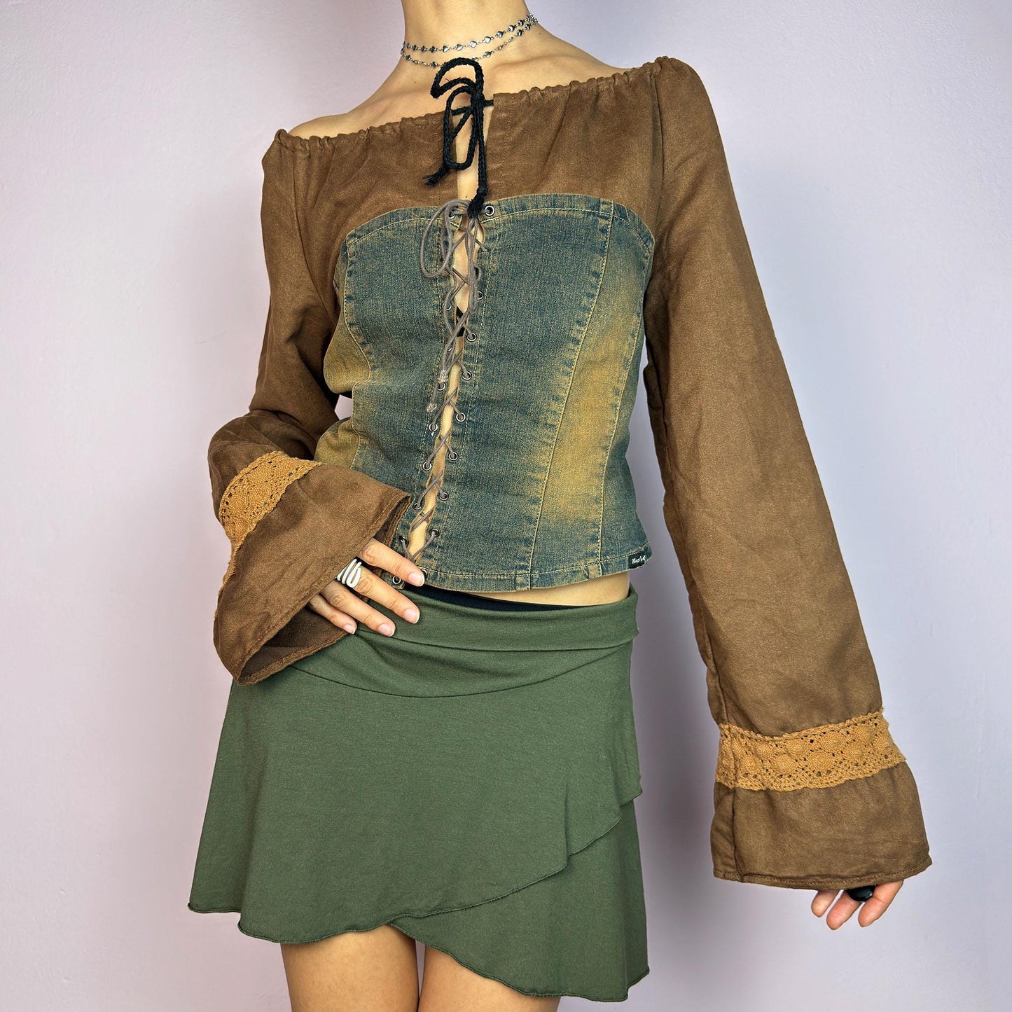 The Y2K Brown Denim Corset Top is a vintage 2000s statement piece blending earthy tones. Crafted with faux suede, this off-the-shoulder top features flared bell long sleeves adorned with crochet lace accents. adult world shop