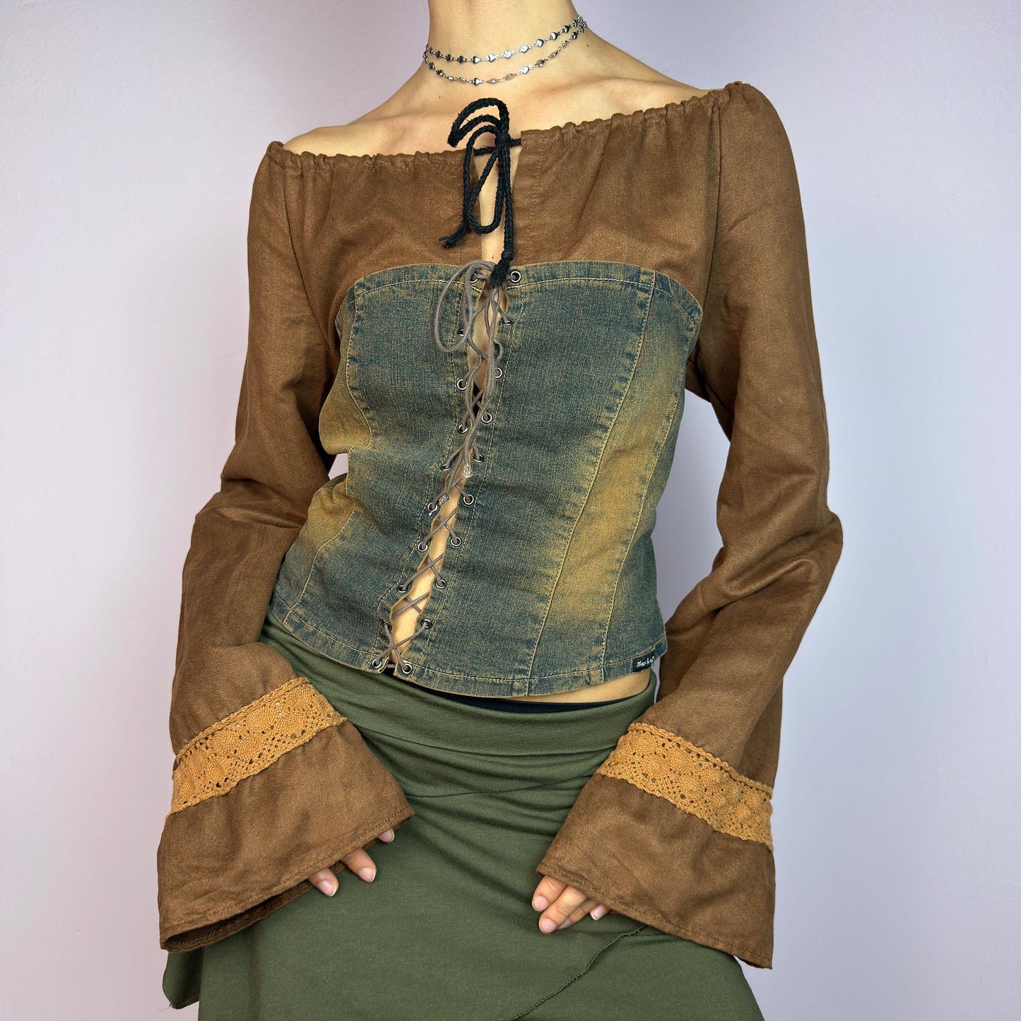 The Y2K Brown Denim Corset Top is a vintage 2000s statement piece blending earthy tones. Crafted with faux suede, this off-the-shoulder top features flared bell long sleeves adorned with crochet lace accents. adult world shop