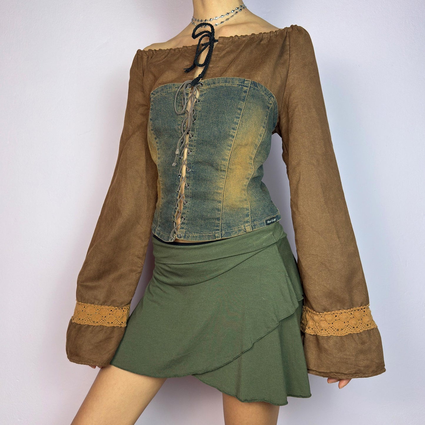 The Y2K Brown Denim Corset Top is a vintage 2000s statement piece blending earthy tones. Crafted with faux suede, this off-the-shoulder top features flared bell long sleeves adorned with crochet lace accents. adult world shop