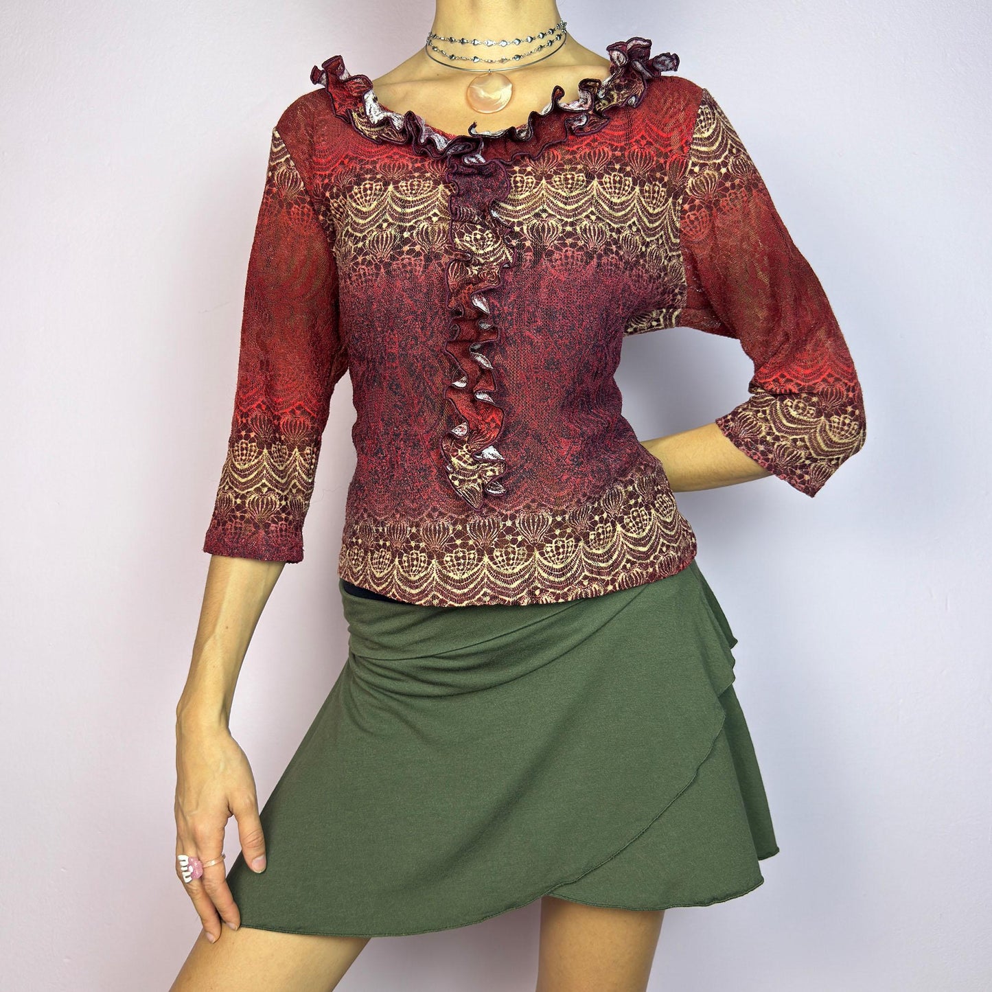 The Y2K Maroon Ruffle Mesh Top is a romantic vintage 2000s piece. Featuring a semi-sheer lace-inspired design in warm red tones, it showcases intricate patterns complemented by a ruffled neckline and 3/4 sleeves. adult world shop