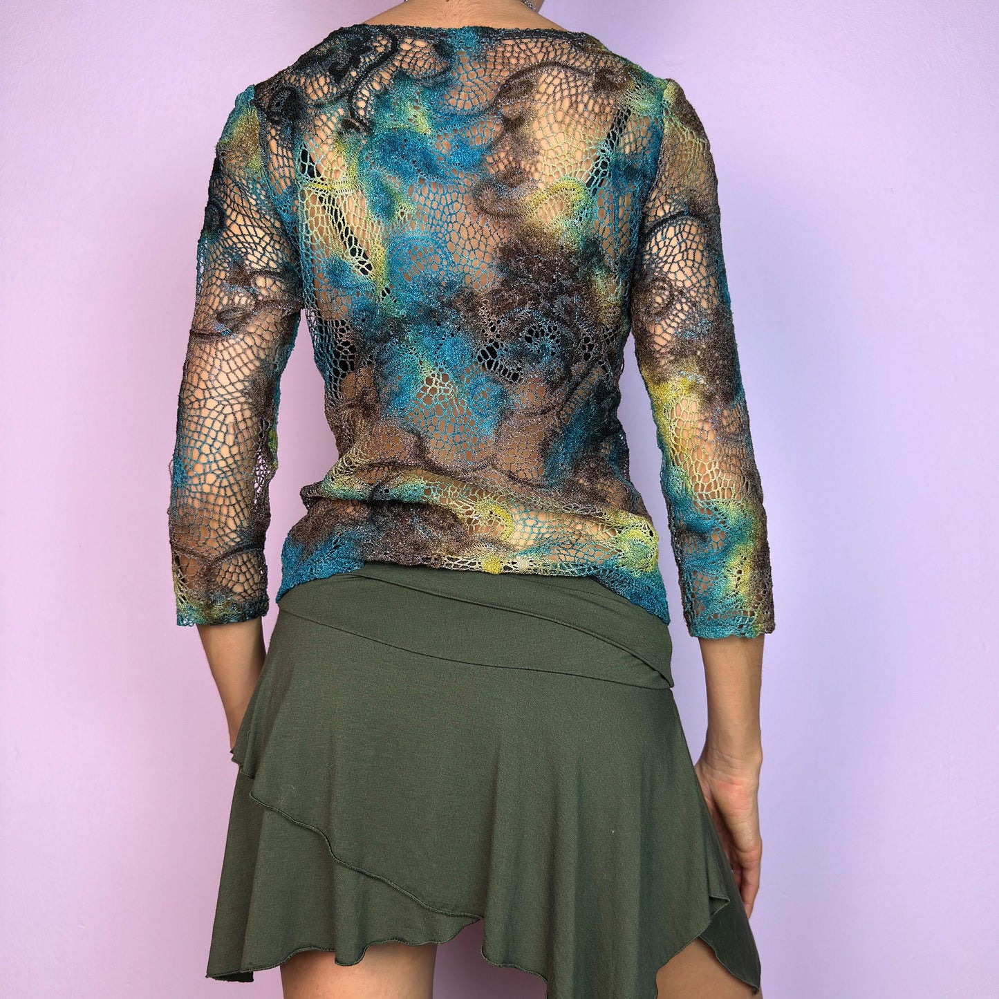 The Y2K Open Knit Mesh Top is a unique vintage 2000s piece featuring an intricate open-knit design, this semi-sheer top boasts a dreamy tie-dye-inspired blend of earthy hues in brown, blue and green. adult world shop