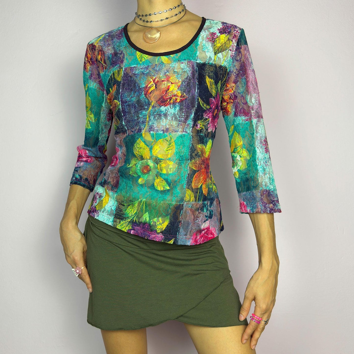 The Y2K Painting Lace Mesh Top is a vintage 2000s artistic statement piece. Featuring a semi-sheer lace fabric adorned with a bold, vibrant floral pattern resembling a painterly masterpiece, a scoop neckline and 3/4 sleeves. adult world shop