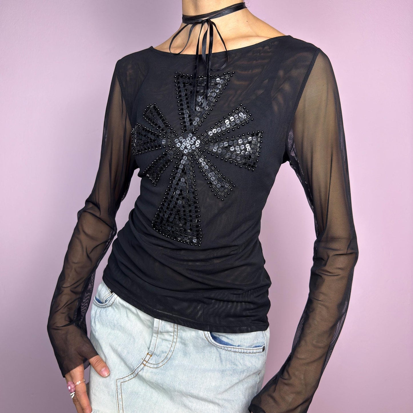 The Y2K Black Embellished Mesh Top is a statement vintage 2000s piece. This sheer top features a bold black sequin and bead embellishment in a striking cross pattern on the front. The lightweight mesh fabric and long sleeves. adult world shop