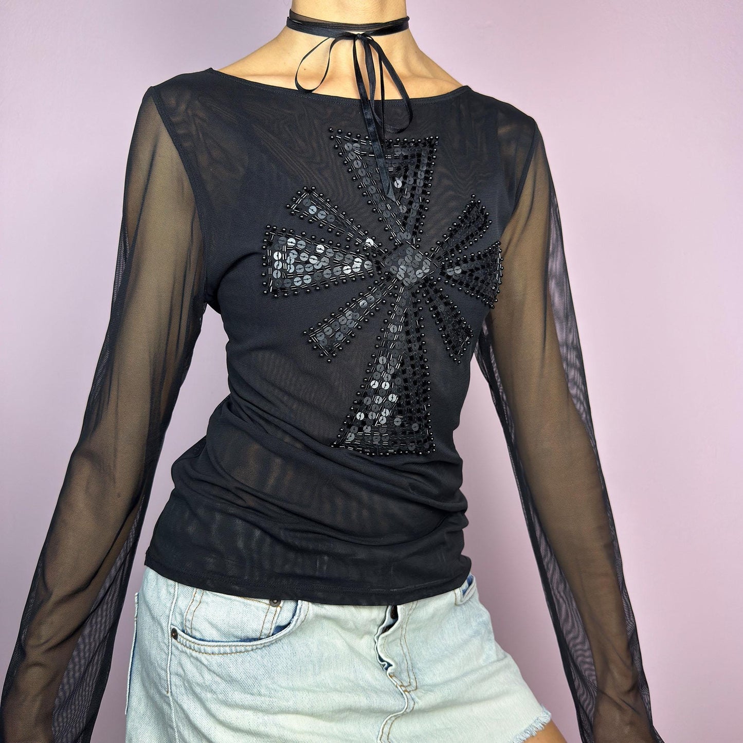 The Y2K Black Embellished Mesh Top is a statement vintage 2000s piece. This sheer top features a bold black sequin and bead embellishment in a striking cross pattern on the front. The lightweight mesh fabric and long sleeves. adult world shop