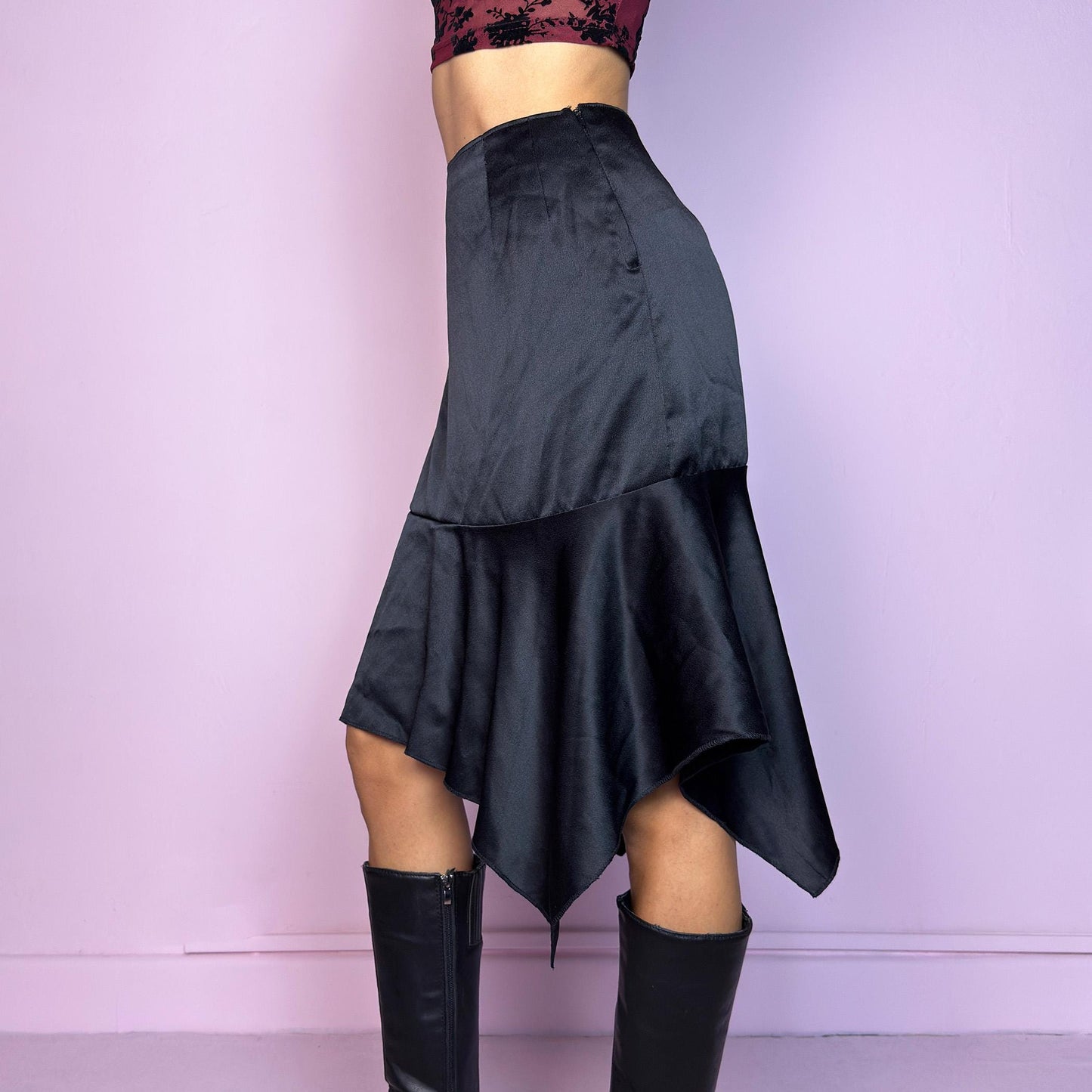 The Y2K Black Satin Asymmetric Skirt is a vintage 2000s stylish piece, featuring a satin-like finish with an asymmetrical handkerchief hemline for a dramatic flair and a size zipper closure. Perfect choice for party nights. Adult World Shop