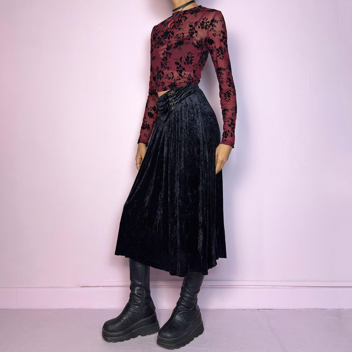 The Vintage 90s Black Velvet Midi Skirt is crafted from soft velvet and features an elastic waistband detail with button accents and a flowing A-line silhouette. Ideal for night parties and embodies a whimsical goth aesthetic. Adult World Shop