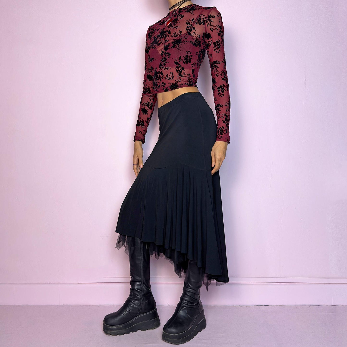 The Vintage 90s Layered Black Midi Skirt features a layered design with an asymmetrical hemline and a delicate tulle underlayer and an elastic waist. The trumpet silhouette enhances the figure, creating a dramatic and elegant flair. Adult World Shop