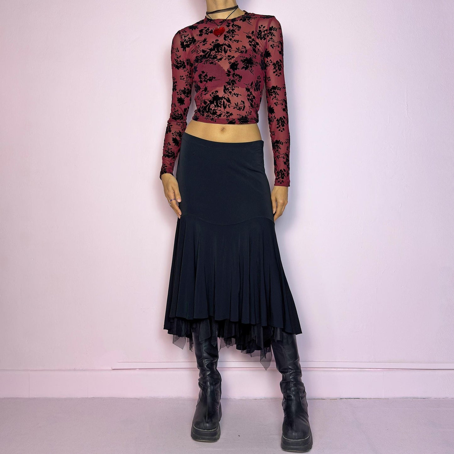The Vintage 90s Layered Black Midi Skirt features a layered design with an asymmetrical hemline and a delicate tulle underlayer and an elastic waist. The trumpet silhouette enhances the figure, creating a dramatic and elegant flair. Adult World Shop