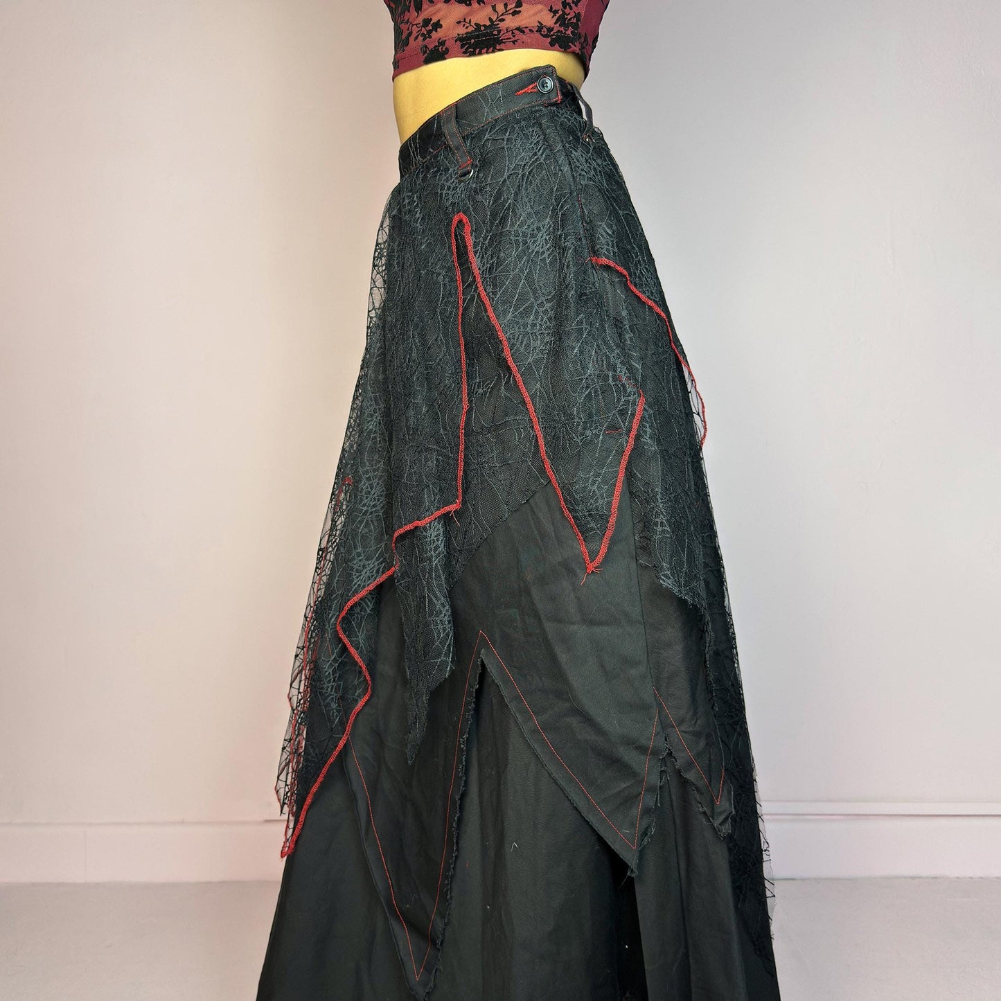 The Black Layered Maxi Skirt is a vintage edgy statement piece crafted by the Japanese punk fashion brand RIGHT? Anarchxism = Kexstation. It features a multi-layered design with mesh web-like overlays, bold red stitching details. Adult World Shop