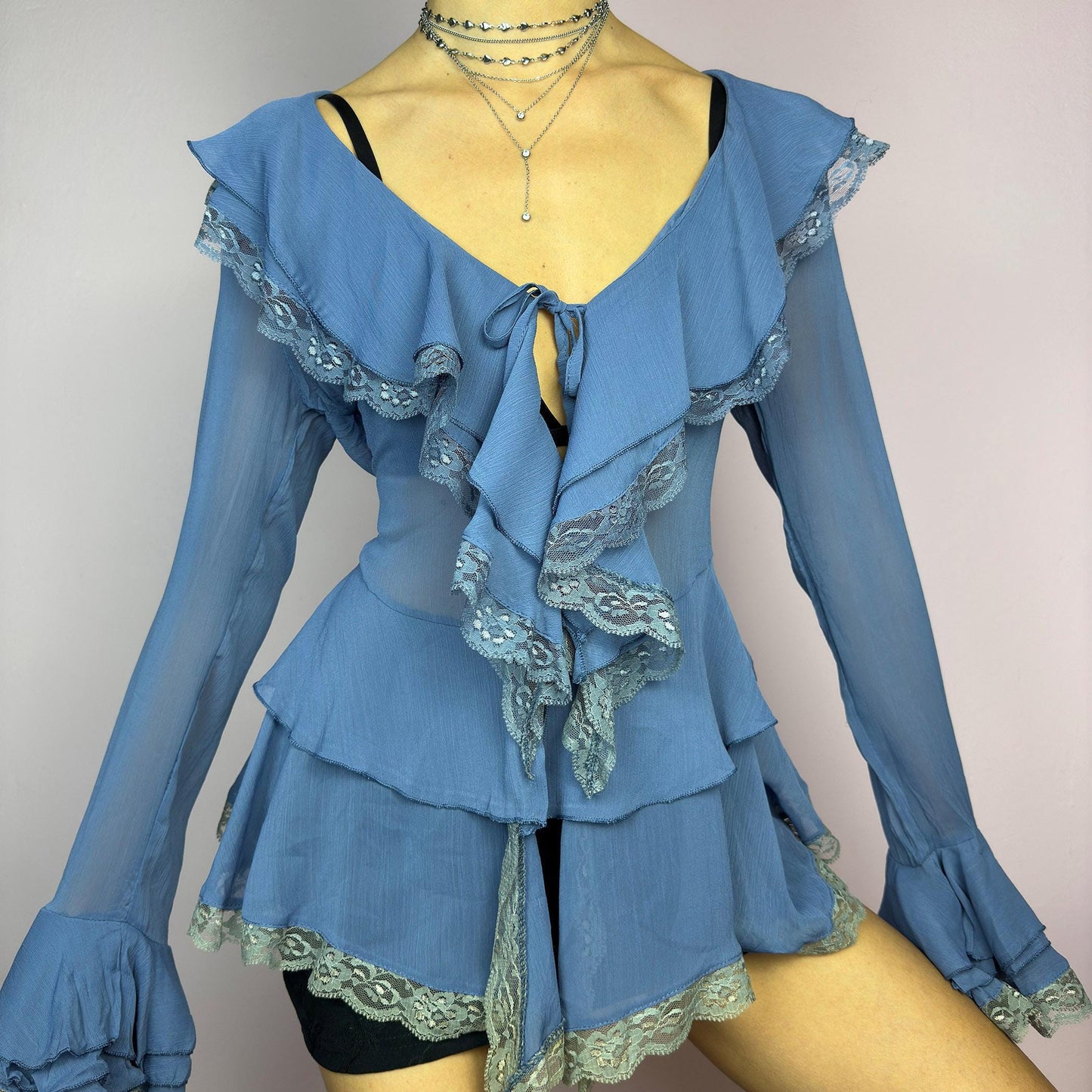 The Y2K Blue Ruffle Blouse is a dreamy vintage 2000s piece with a romantic and ethereal aesthetic. Crafted from a sheer, lightweight fabric in a soft blue shade, this blouse features cascading ruffles with delicate lace trim. adult world shop