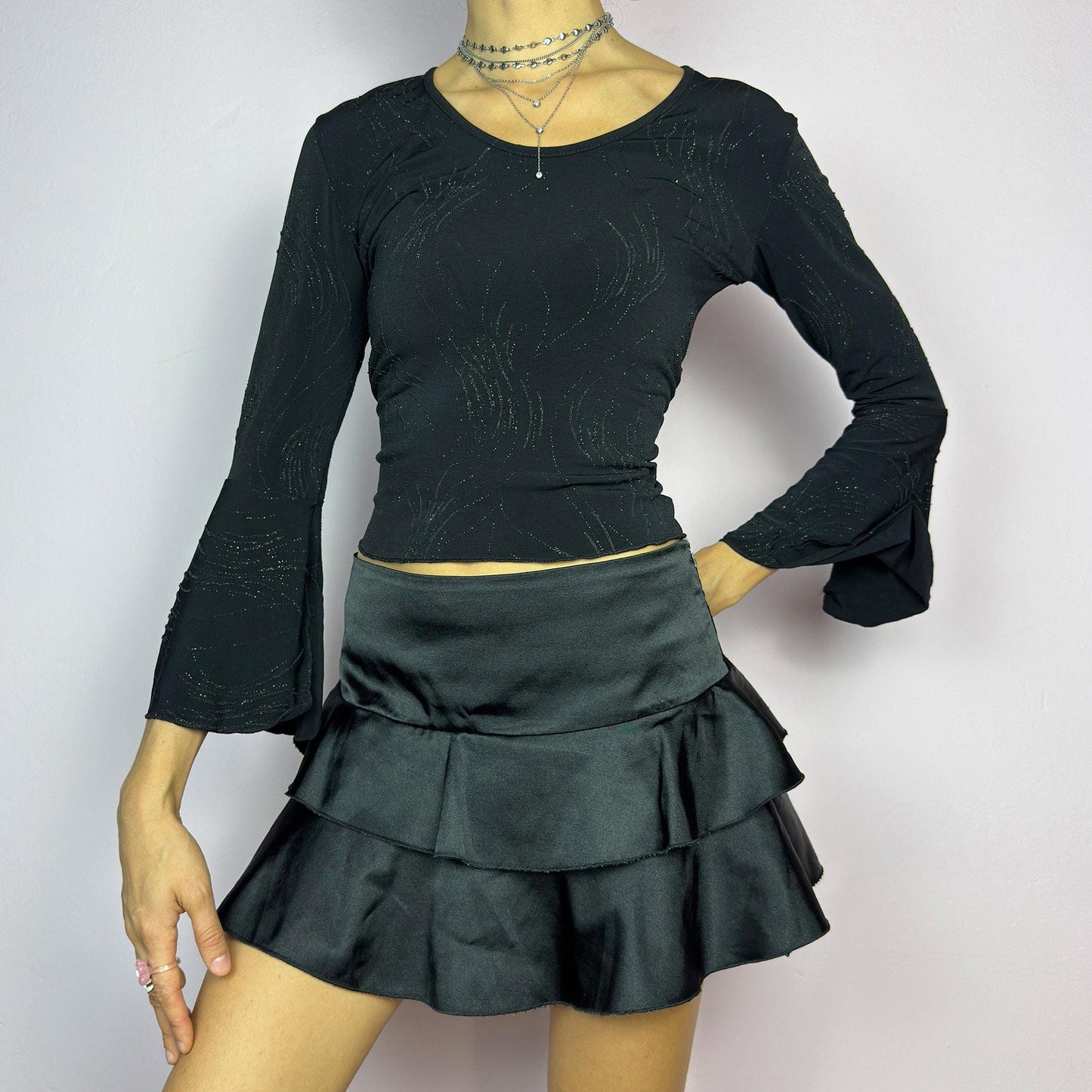 The Y2K Black Ruffle Satin Mini Skirt is a vintage 2000s piece made from a sleek satin-style stretchy fabric featuring layered ruffles, low rise design and a side zipper closure. Ideal for a night-out outfit. adult world shop
