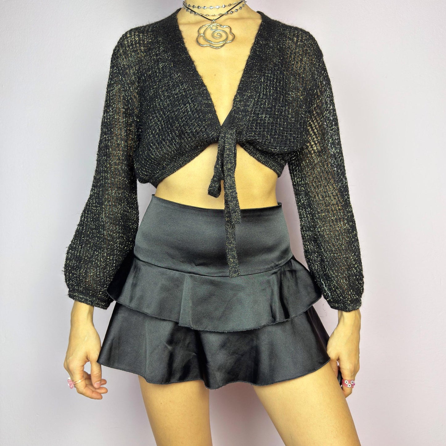 This Y2K Black Tie Front Cardigan is a vintage 2000s piece featuring a lightweight open-knit design with a subtle metallic shimmer, a cropped fit and long sleeves. Perfect for layering and ideal for night-out or casual outfits.