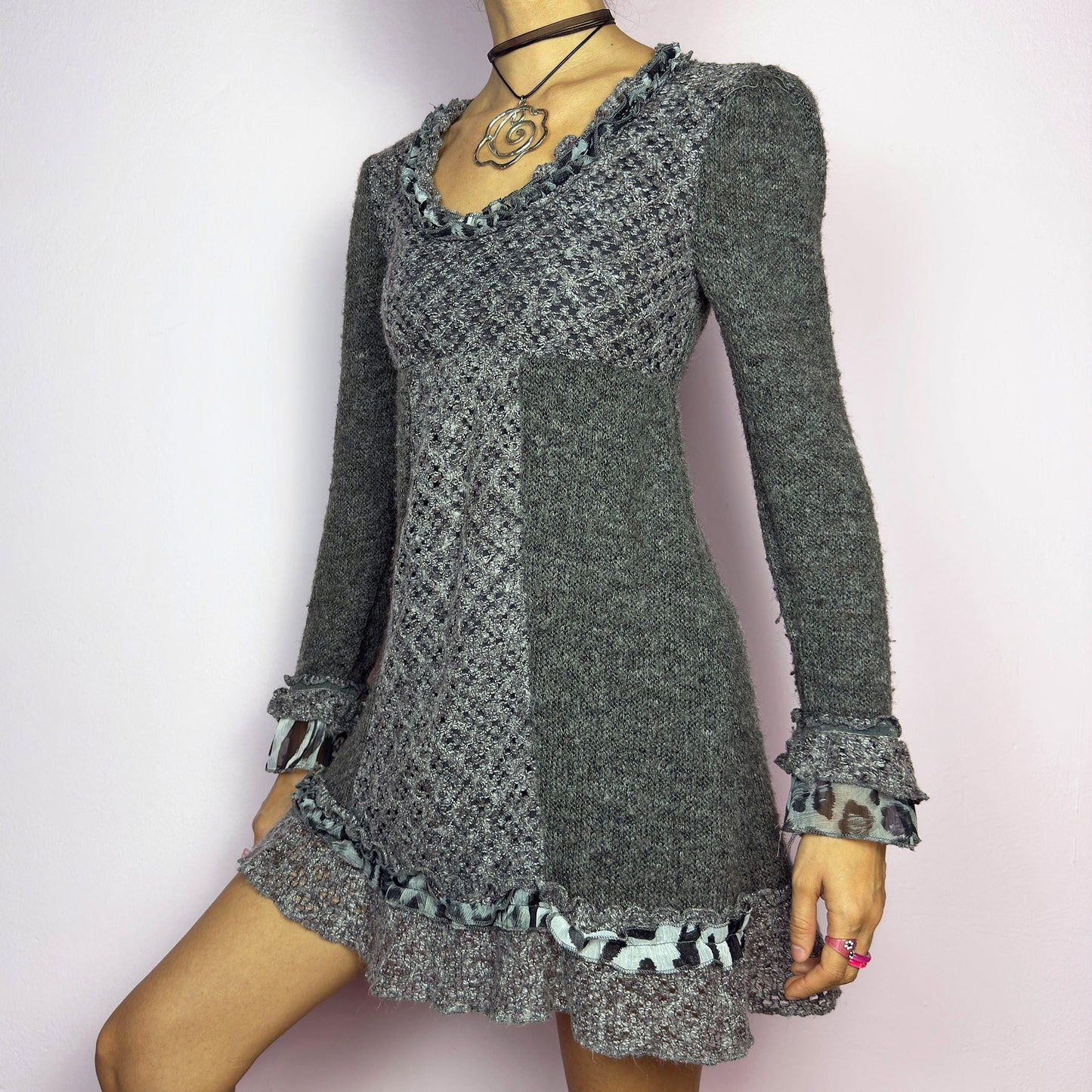 The Y2K Gray Knit Mini Dress is a vintage 2000s piece featuring a patchwork knit design with ruffle trim details. With a fitted bust and flared hem, this dress has a romantic and whimsical aesthetic. The long sleeves add a cozy. adult world shop