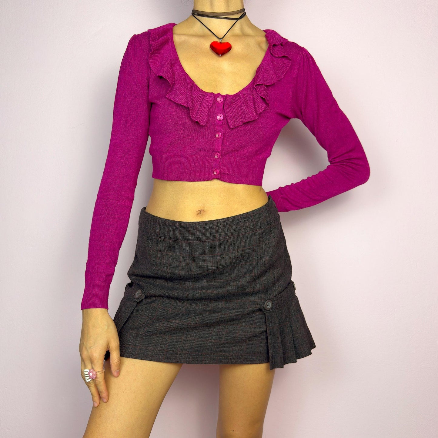 The Y2K Dark Brown Plaid Mini Skirt is a vintage 2000s piece featuring decorative button with pleated panel details on each side. Made from a thick woven fabric with a subtle plaid pattern, it has a side zipper closure. adult world shop