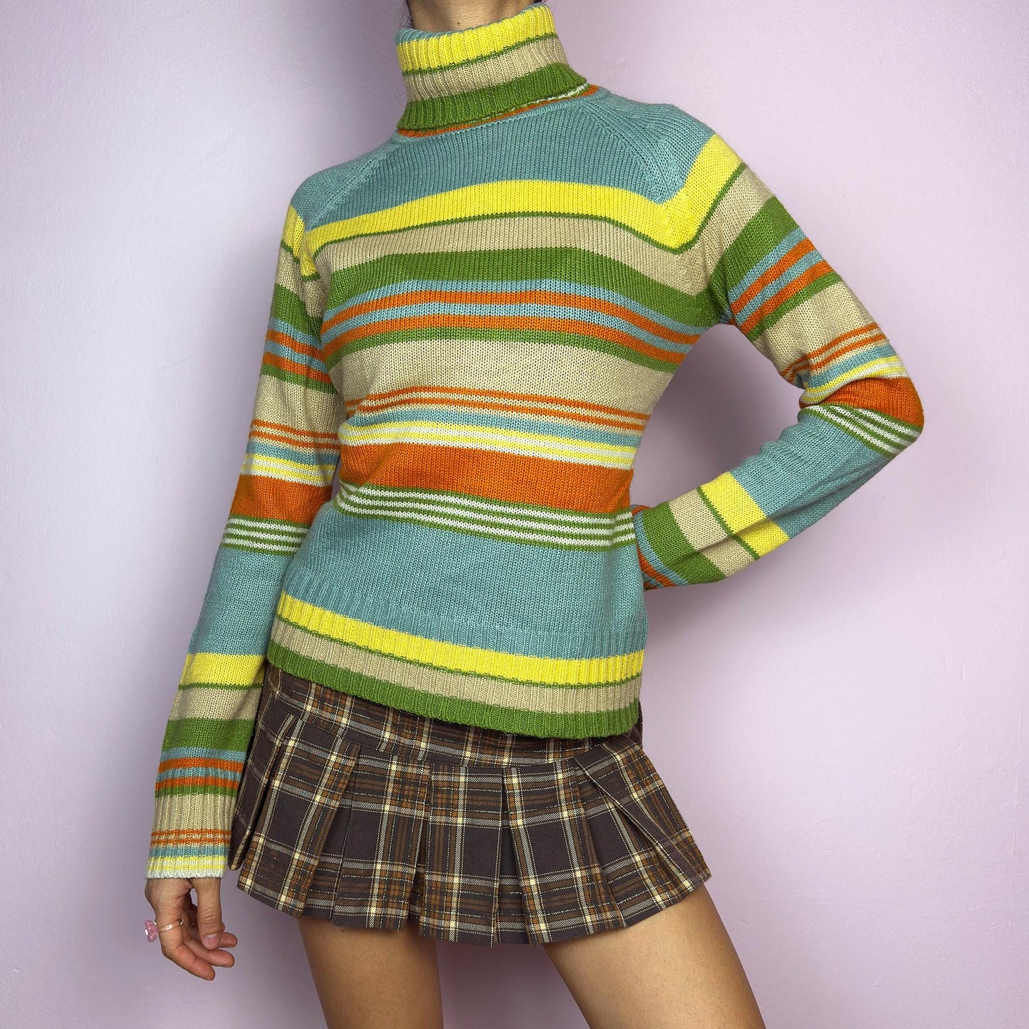 The Y2K Striped Turtleneck Sweater is a vintage 2000s classic featuring a cozy ribbed turtleneck design. Crafted from a knit fabric, it showcases bold multicolor horizontal stripes. adult world shop