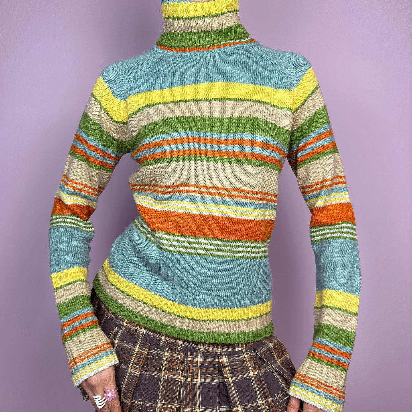 The Y2K Striped Turtleneck Sweater is a vintage 2000s classic featuring a cozy ribbed turtleneck design. Crafted from a knit fabric, it showcases bold multicolor horizontal stripes. adult world shop