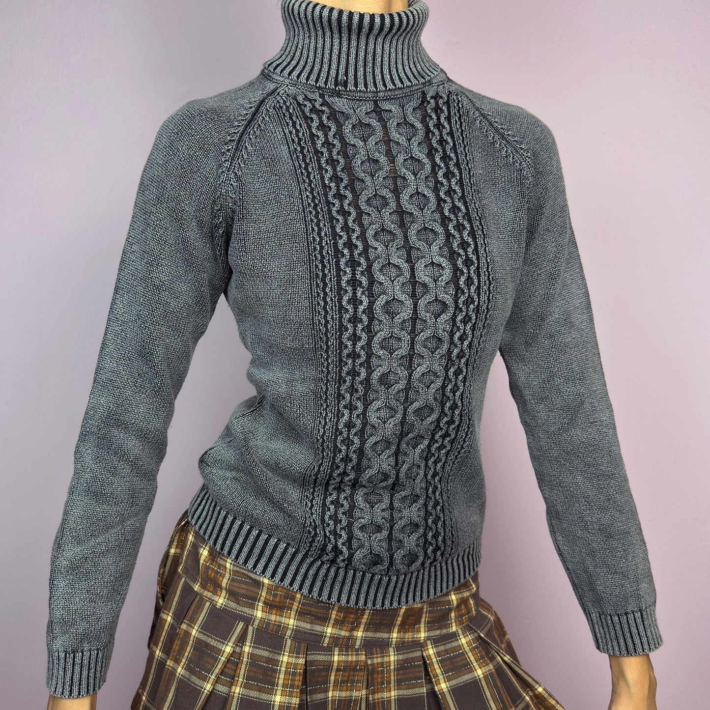 The Y2K Washed Gray Turtleneck Sweater is a vintage 2000s piece, featuring a slightly faded gray tone for a worn-in, effortless look. Designed with an intricate cable knit pattern on the front, ribbed cuffs, and a thick turtleneck, it offers both warmth and style. Ideal for preppy, academia, or casual winter outfits. adult world shop