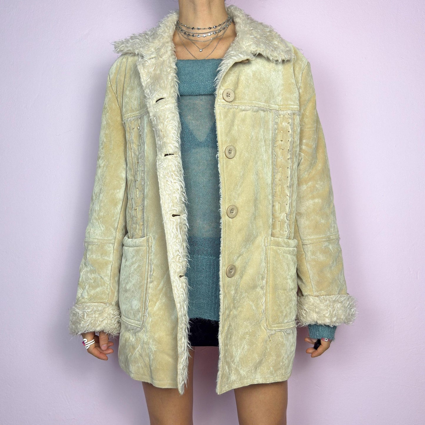 The Y2K Beige Faux Fur Suede Jacket is a vintage 2000s cozy outerwear piece featuring a soft faux suede finish in a beige tone, a faux shearling-lined collar and cuffs for added warmth, a button-front closure and pockets. adult world shop