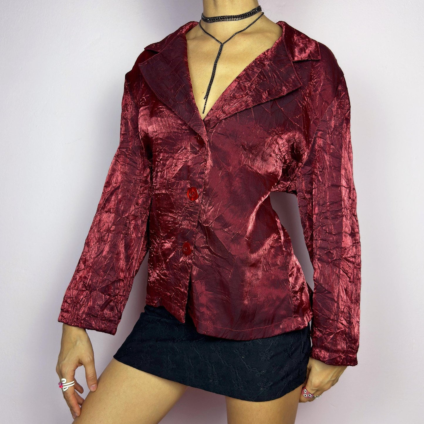 The Vintage 90s Red Iridescent Jacket is a striking and glamorous piece featuring a textured, crinkled design with a luxurious, iridescent sheen. This button-up jacket showcases a deep red tone, wide lapels, and bold red buttons. adult world shop