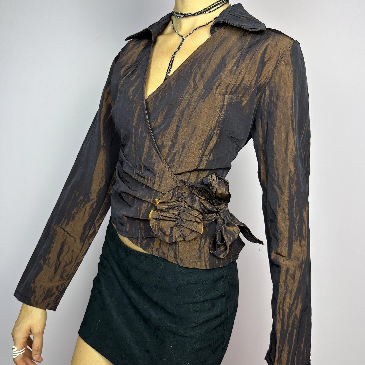 The Vintage 90s Brown Wrap Tie Blouse features a textured, crinkled fabric with a subtle iridescent finish, a flattering wrap design with a tie at the side. The deep brown tone adds versatility, while the structured collar. adult world shop