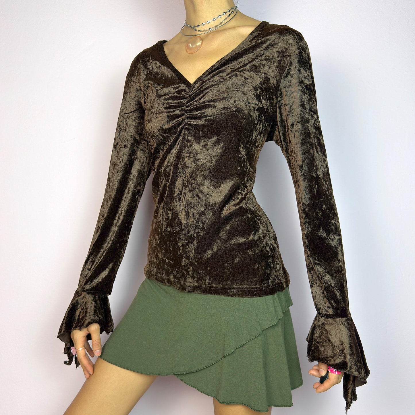 The Vintage 90s Brown Velvet Top is an elegant piece crafted from soft, stretchy velvet fabric. It features a rich chocolate brown hue, a flattering V-neckline with ruching detail at the bust, and dramatic bell sleeves. adult world shop