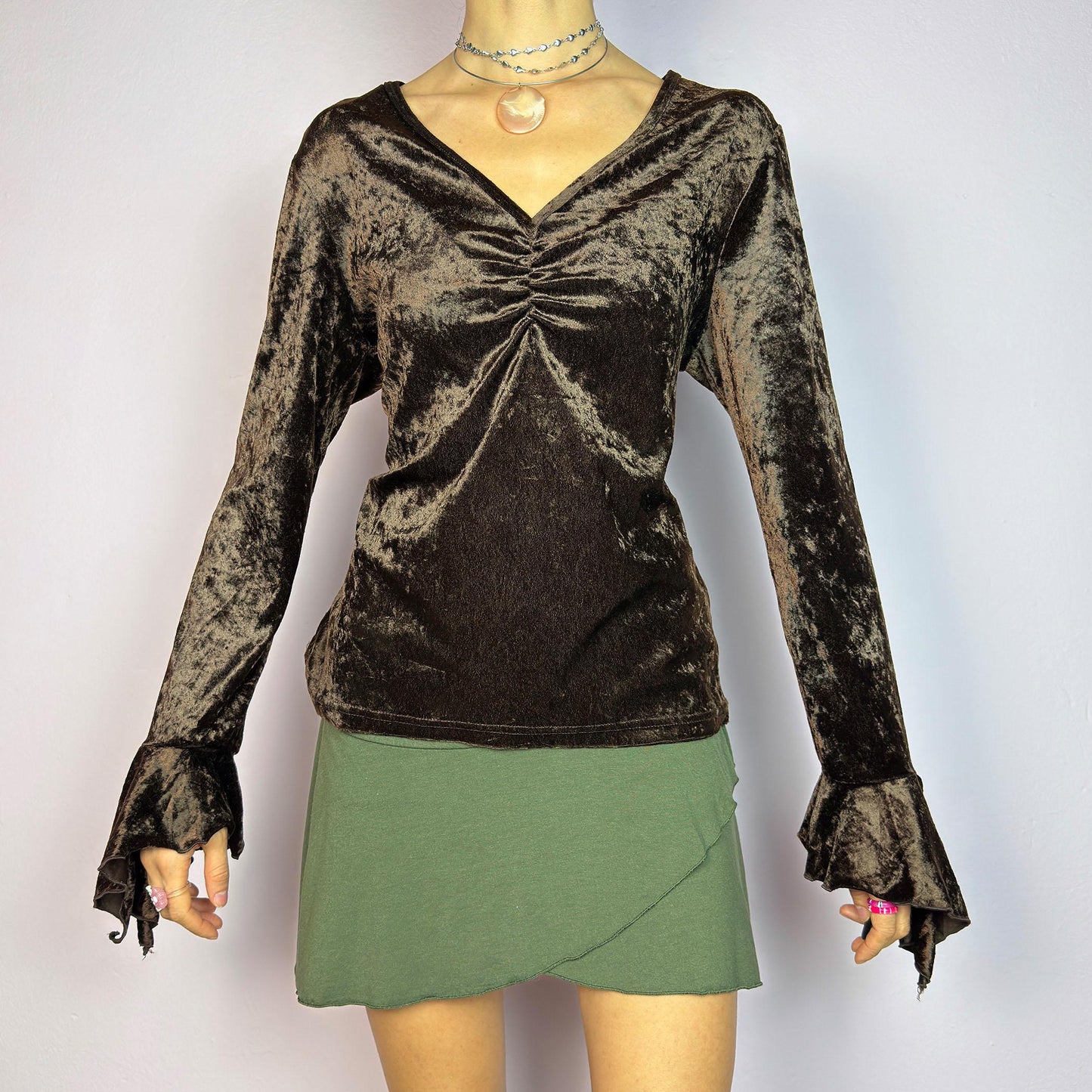 The Vintage 90s Brown Velvet Top is an elegant piece crafted from soft, stretchy velvet fabric. It features a rich chocolate brown hue, a flattering V-neckline with ruching detail at the bust, and dramatic bell sleeves. adult world shop