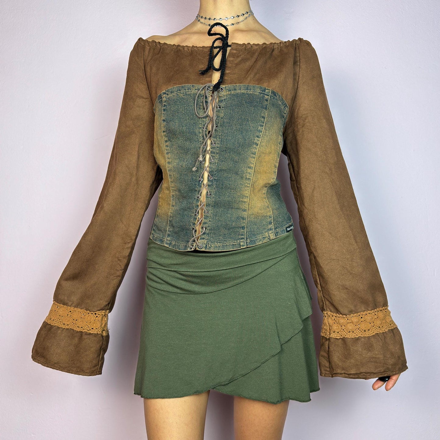 The Y2K Brown Denim Corset Top is a vintage 2000s statement piece blending earthy tones. Crafted with faux suede, this off-the-shoulder top features flared bell long sleeves adorned with crochet lace accents. adult world shop