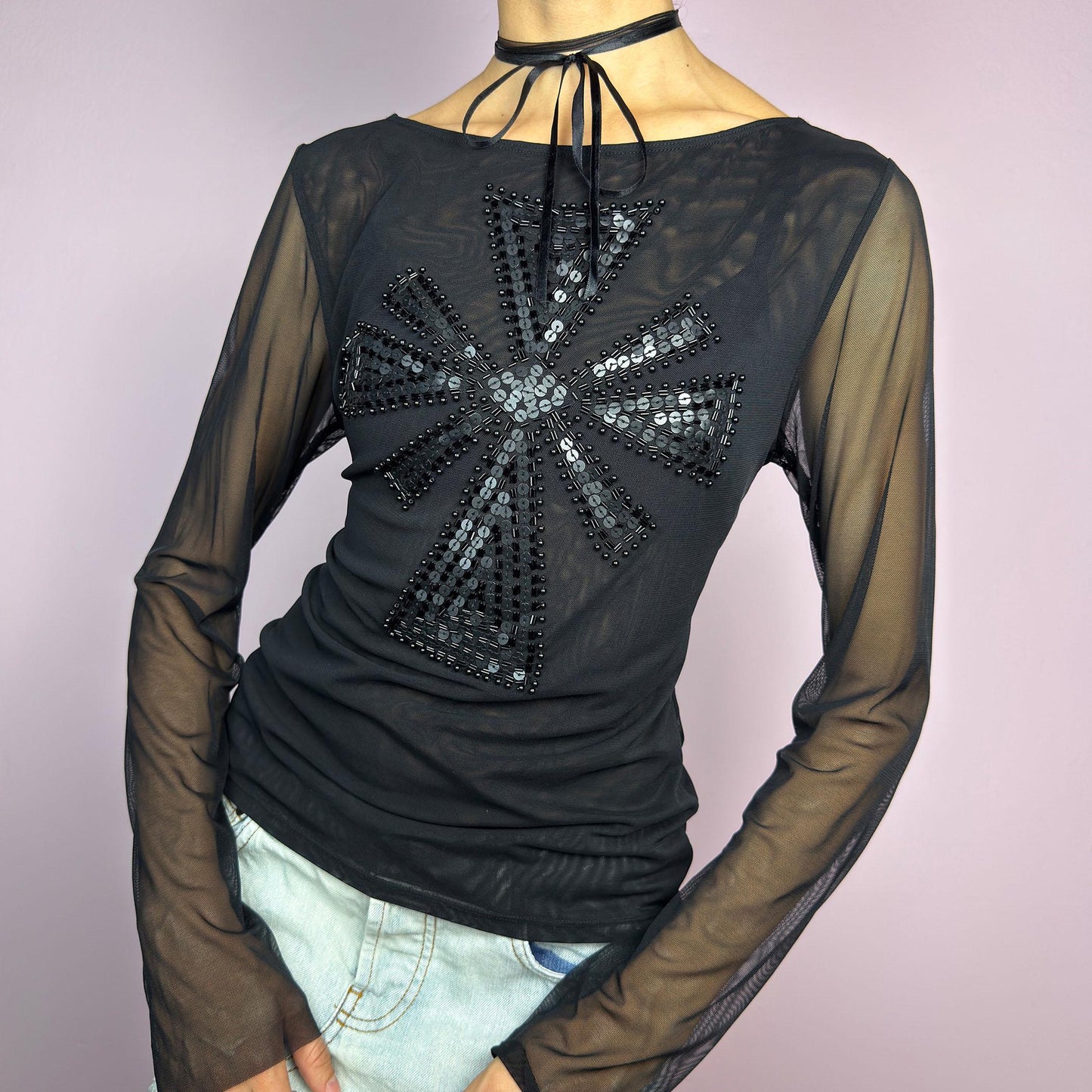 The Y2K Black Embellished Mesh Top is a statement vintage 2000s piece. This sheer top features a bold black sequin and bead embellishment in a striking cross pattern on the front. The lightweight mesh fabric and long sleeves. adult world shop