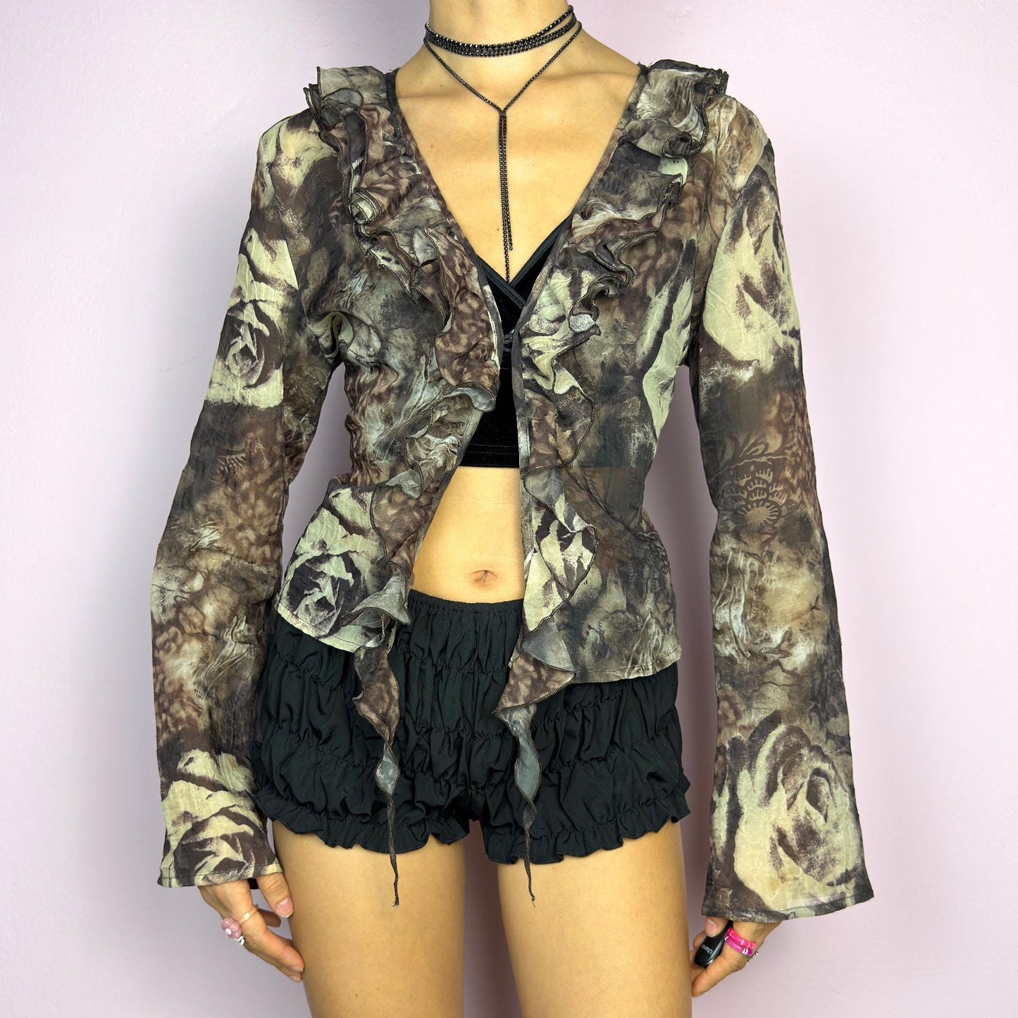 The Y2K Printed Ruffle Blouse is a stunning vintage 2000s romantic piece crafted from sheer, lightweight fabric in brown tones and featuring a blend of earthy hues in a rose-patterned print. adult world shop