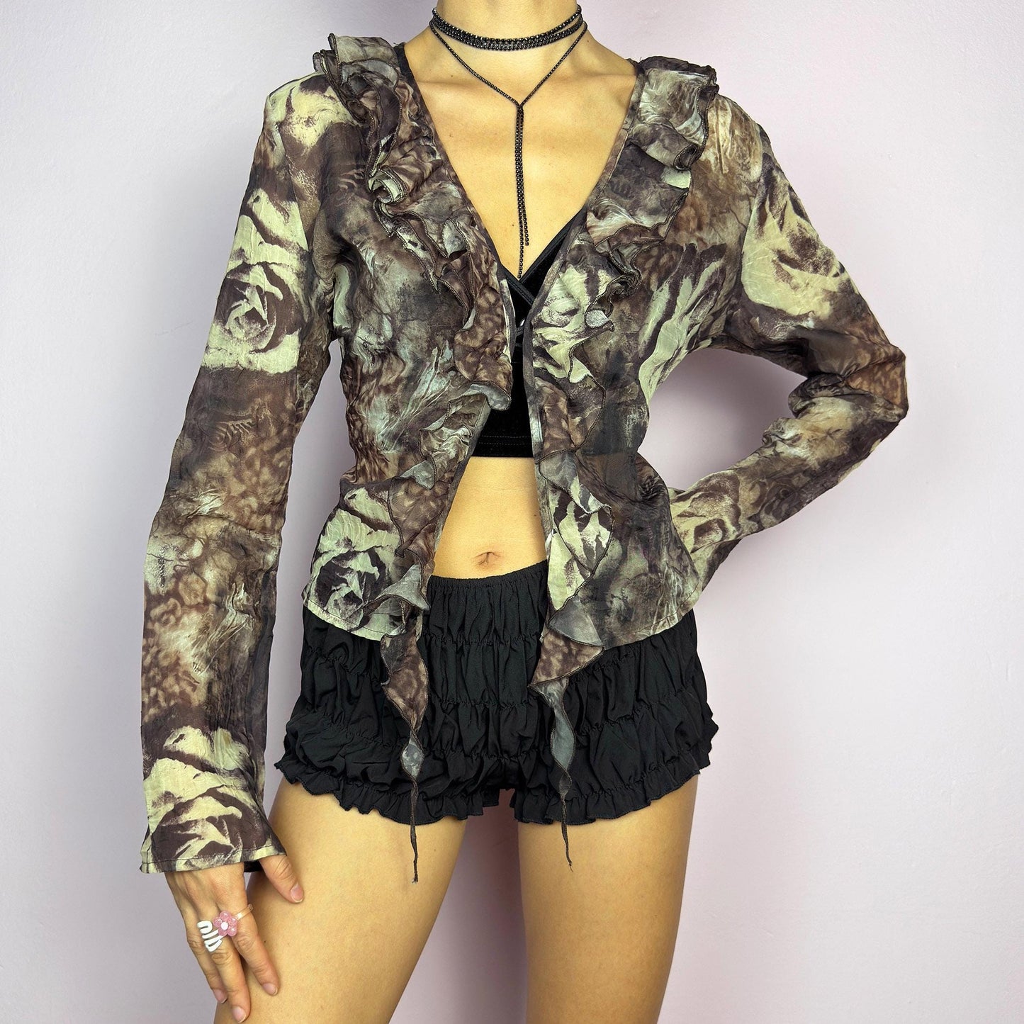 The Y2K Printed Ruffle Blouse is a stunning vintage 2000s romantic piece crafted from sheer, lightweight fabric in brown tones and featuring a blend of earthy hues in a rose-patterned print. adult world shop