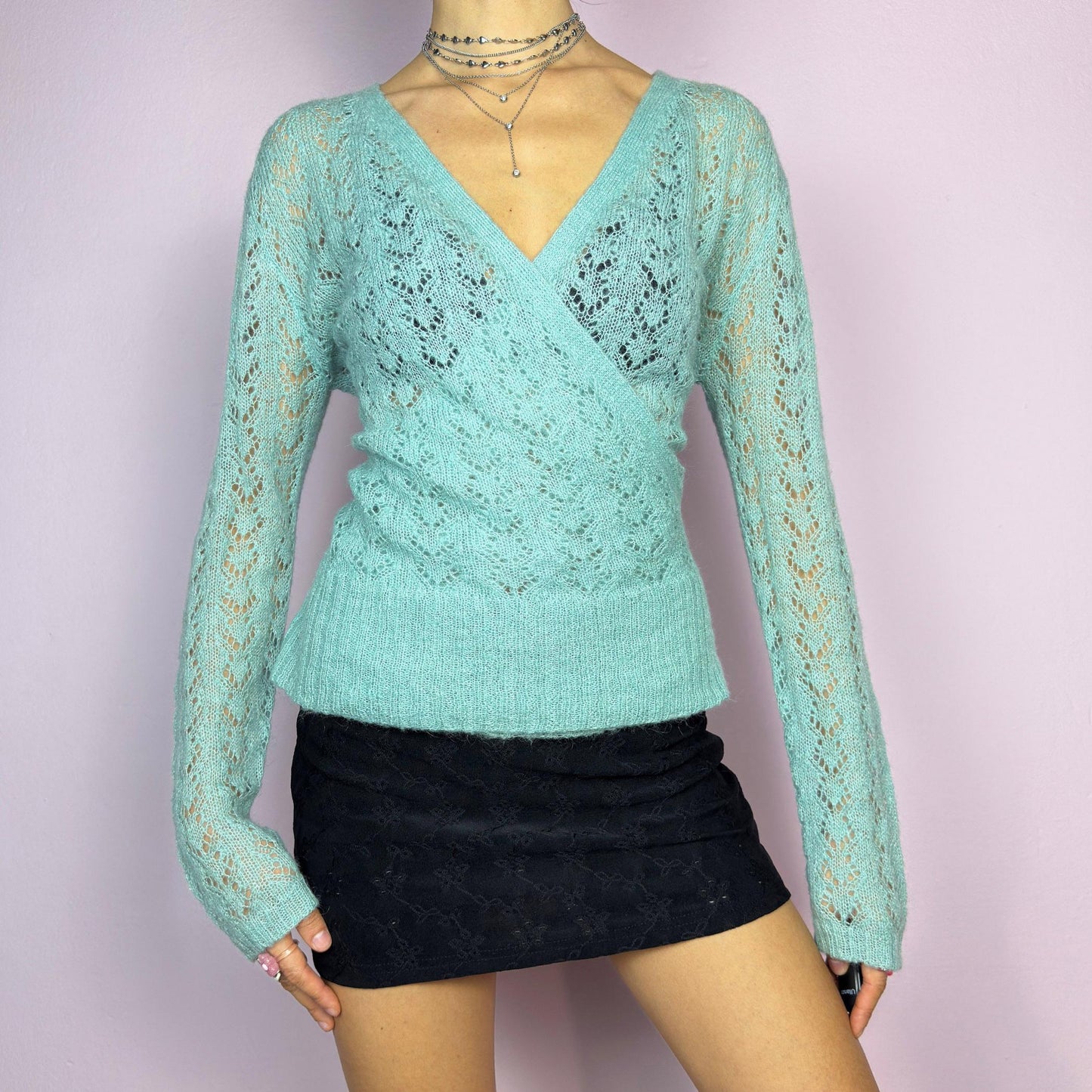 The Y2K Blue Wrap Tie Cardigan is a soft and delicate vintage 2000s piece perfect for layering. Made from a cozy open-knit fabric in a dreamy pastel blue, this cardigan features a wrap-style front with a fitted waist and long sleeve. adult world shop