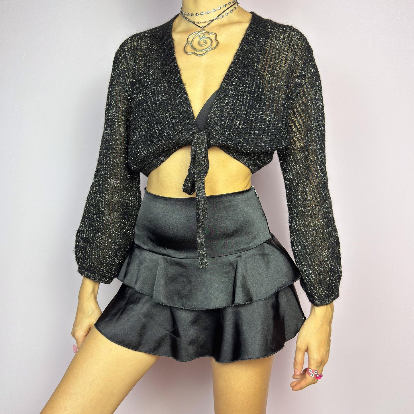 This Y2K Black Tie Front Cardigan is a vintage 2000s piece featuring a lightweight open-knit design with a subtle metallic shimmer, a cropped fit and long sleeves. Perfect for layering and ideal for night-out or casual outfits.