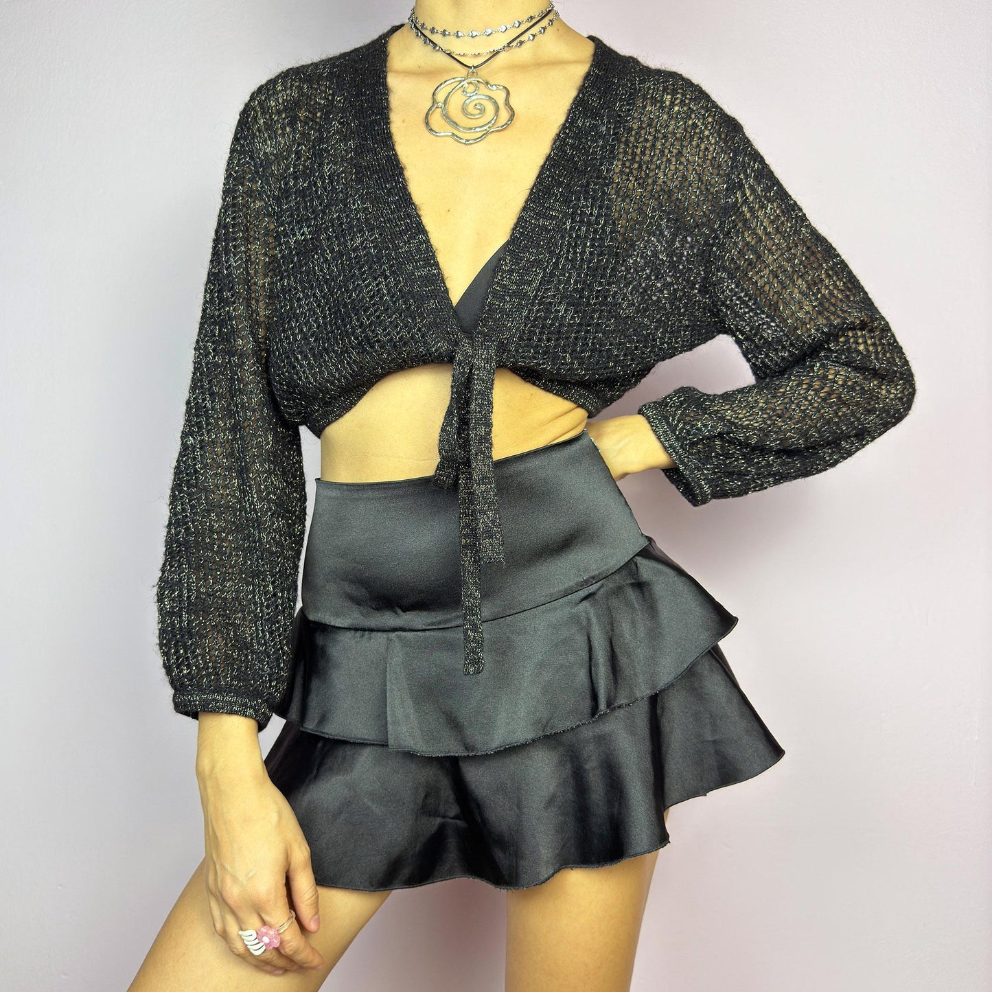 This Y2K Black Tie Front Cardigan is a vintage 2000s piece featuring a lightweight open-knit design with a subtle metallic shimmer, a cropped fit and long sleeves. Perfect for layering and ideal for night-out or casual outfits.