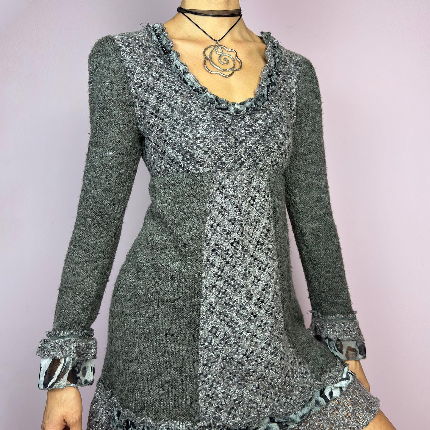 The Y2K Gray Knit Mini Dress is a vintage 2000s piece featuring a patchwork knit design with ruffle trim details. With a fitted bust and flared hem, this dress has a romantic and whimsical aesthetic. The long sleeves add a cozy. adult world shop