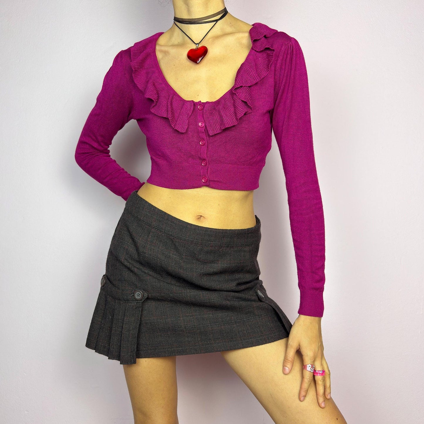 The Y2K Dark Brown Plaid Mini Skirt is a vintage 2000s piece featuring decorative button with pleated panel details on each side. Made from a thick woven fabric with a subtle plaid pattern, it has a side zipper closure. adult world shop