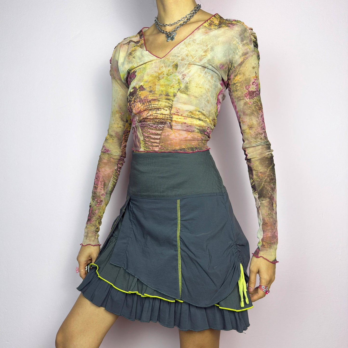 The Y2K Gray Ruffle Mini Skirt is a vintage 2000s statement piece featuring a tiered layered design with yellow contrast stitching details. Designed with a high-waist fit, it includes a side zipper closure. adult world shop
