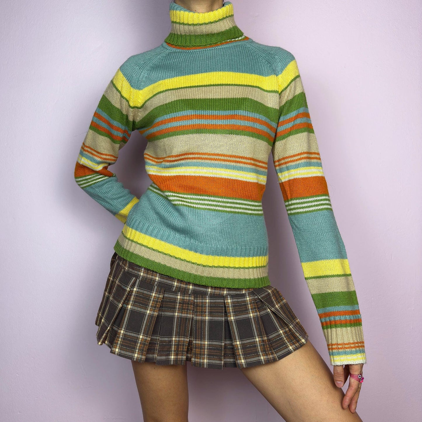 The Y2K Striped Turtleneck Sweater is a vintage 2000s classic featuring a cozy ribbed turtleneck design. Crafted from a knit fabric, it showcases bold multicolor horizontal stripes. adult world shop