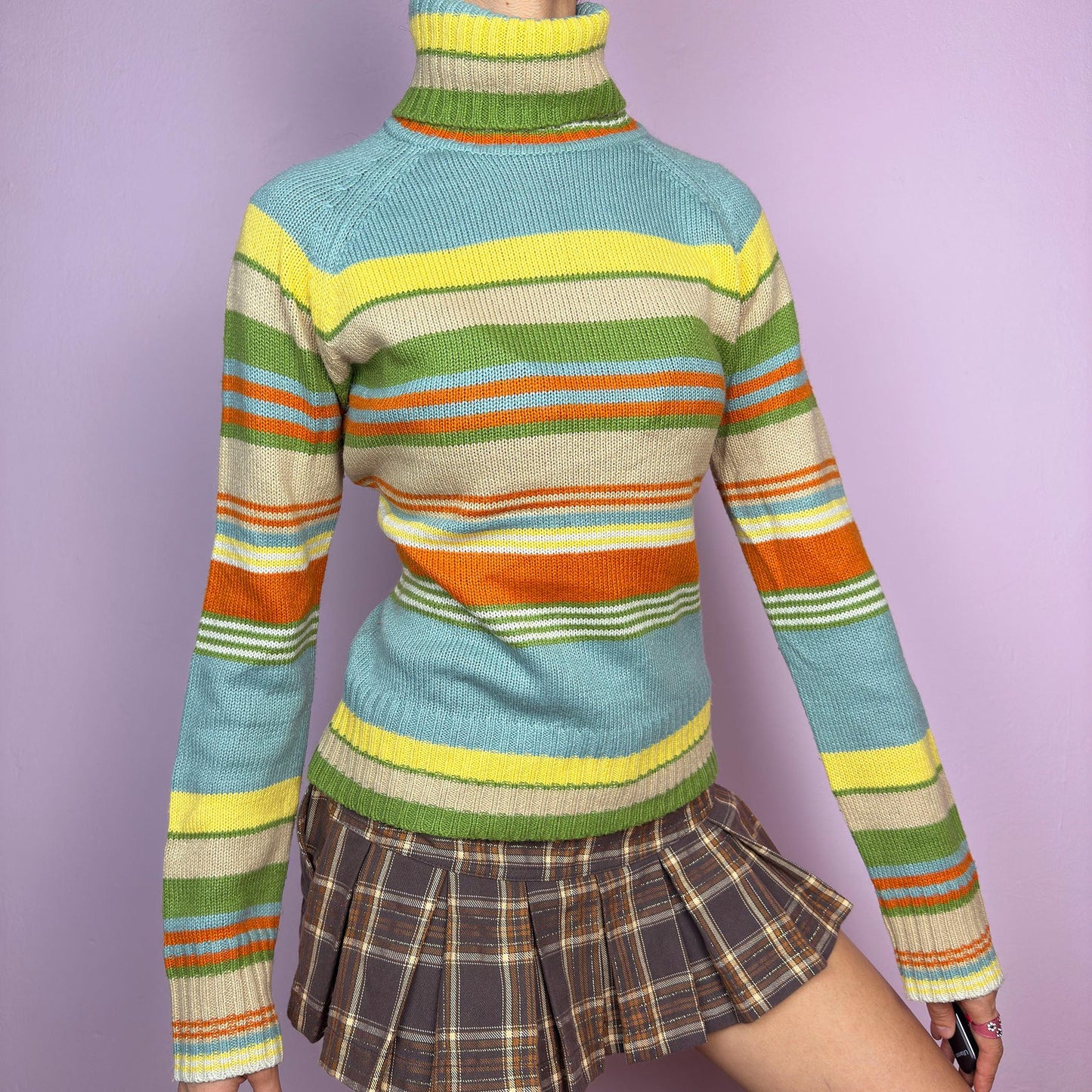 The Y2K Striped Turtleneck Sweater is a vintage 2000s classic featuring a cozy ribbed turtleneck design. Crafted from a knit fabric, it showcases bold multicolor horizontal stripes. adult world shop